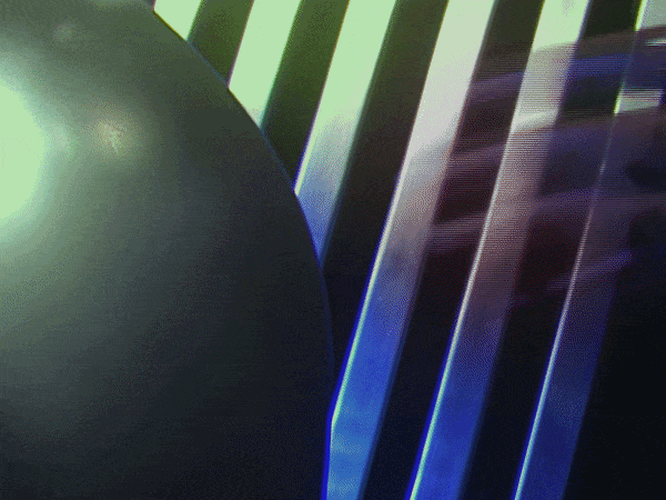 Close-up of a black spherical object next to illuminated, colorful, diagonal LED light bars.