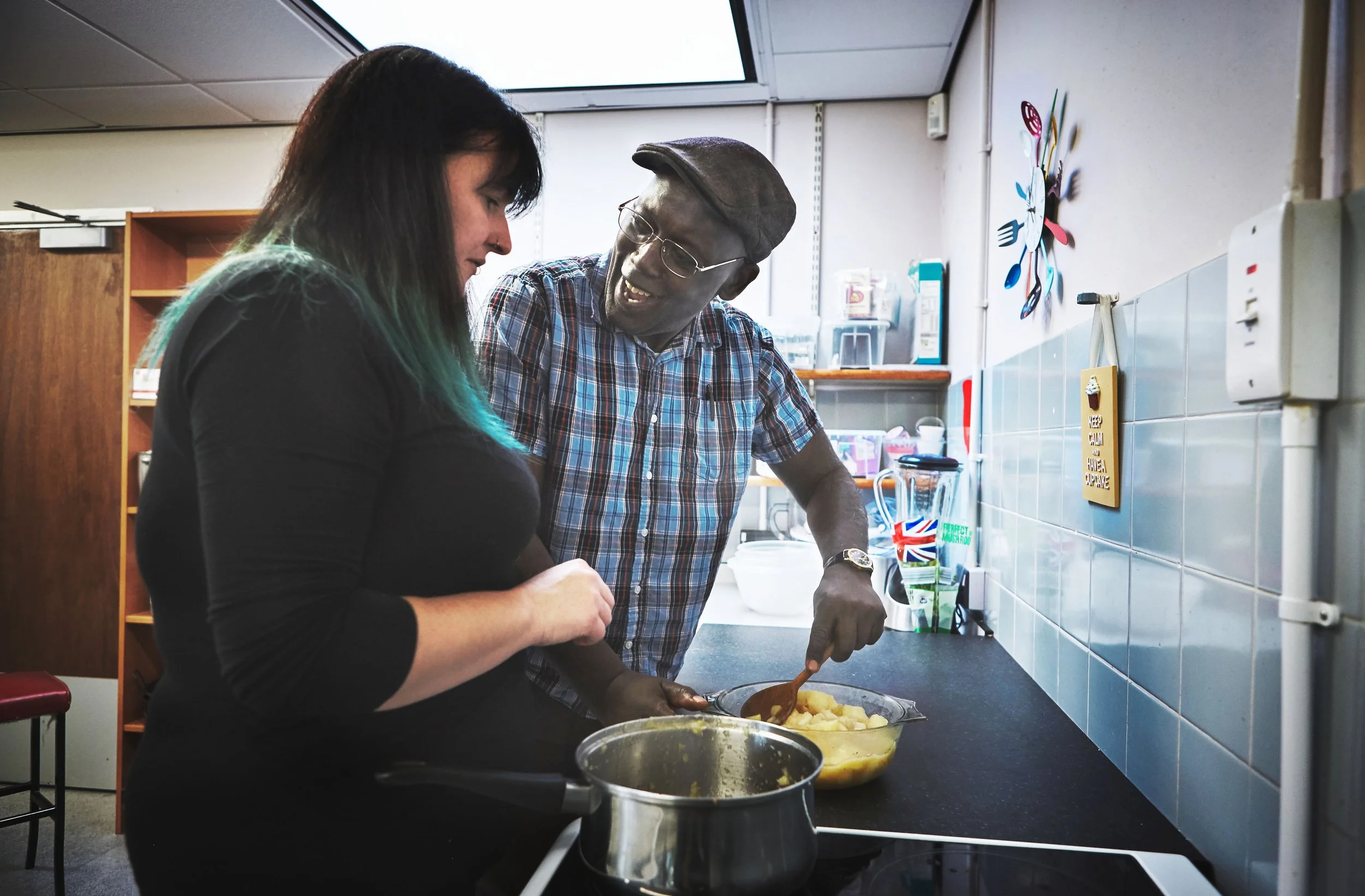 Two vocational therapy members at MARC cooking together in a kitchen, with one man helping the woman prepare food.