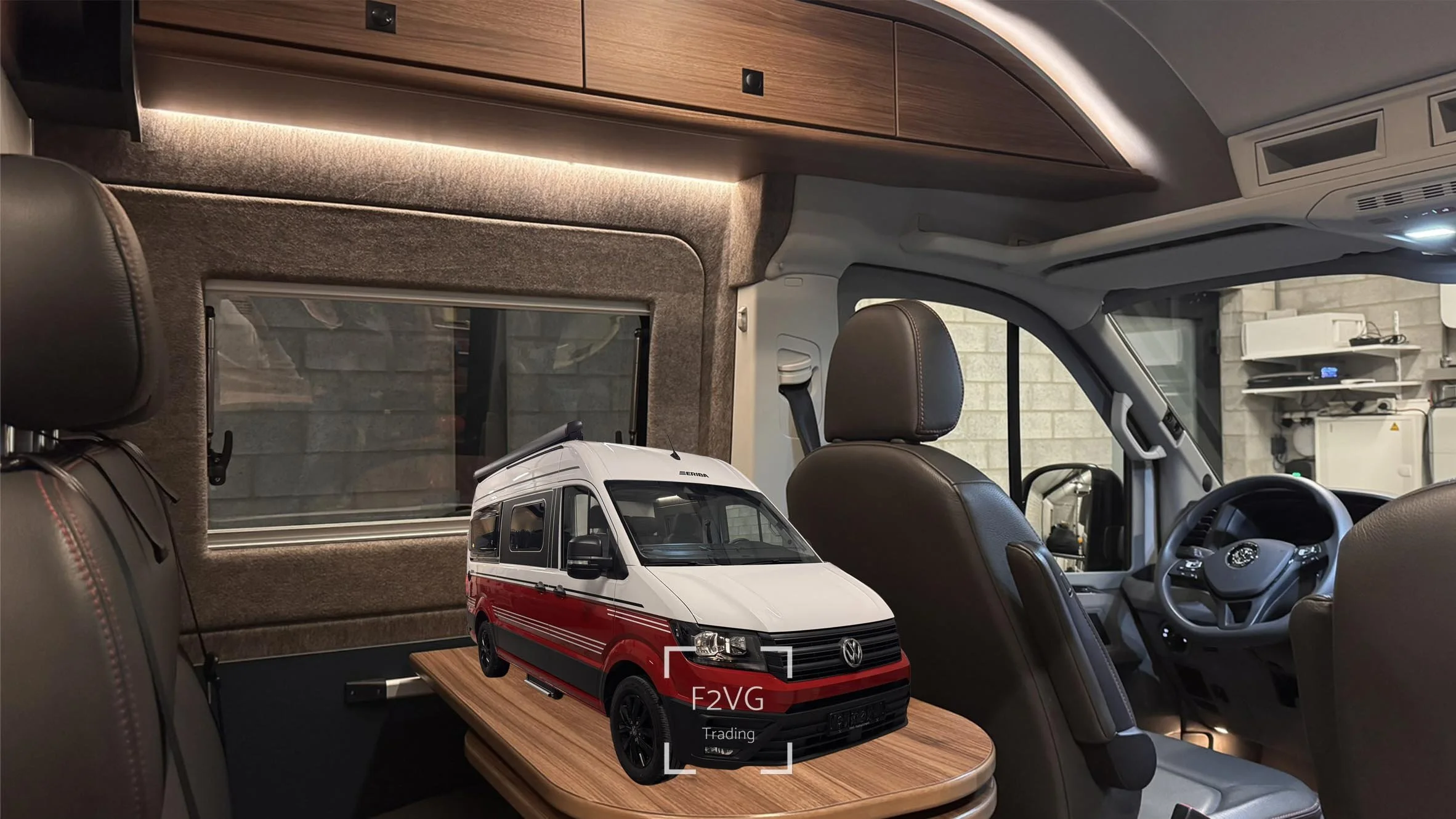 Interieur van een camper of bus met zicht op het bestuurdersgedeelte en een tafel met een model van een witte en rode Van Volkswagen.