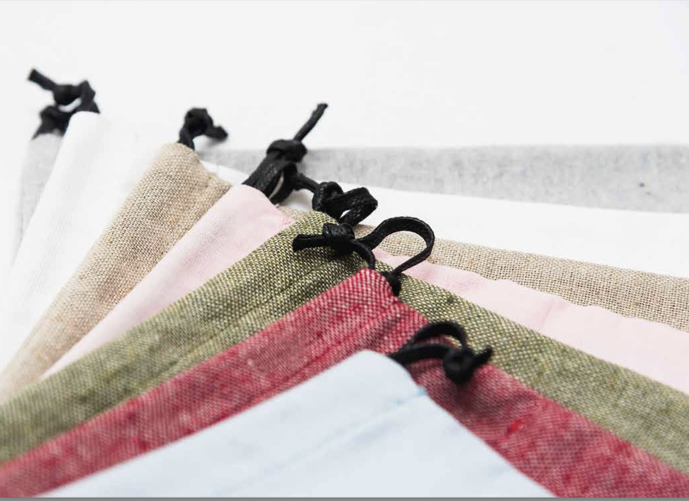 Close-up of assorted fabrics with black elastic ear loops, arranged overlapping on a white background.