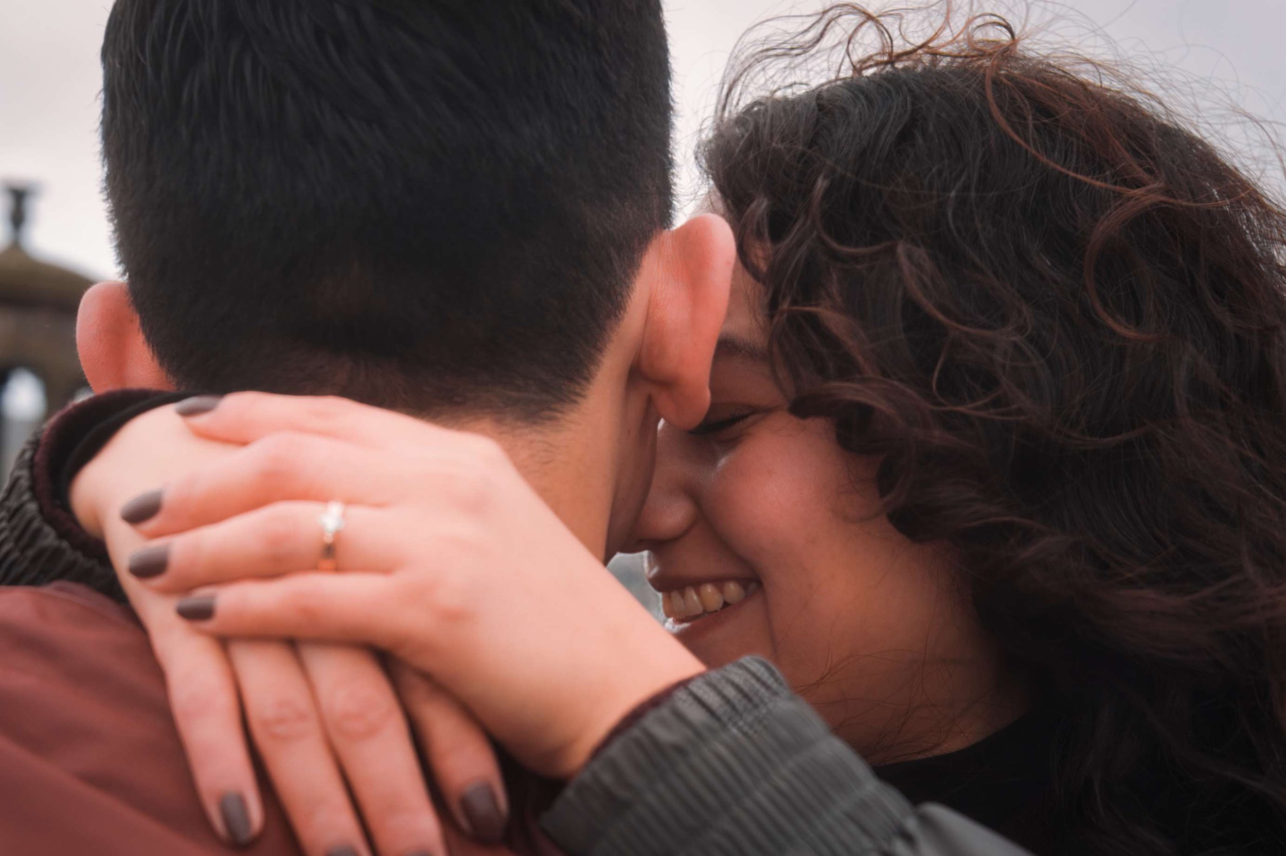 Close-up of a couple embracing closely, smiling, with heads touching, showing their hair and faces, conveying intimacy and affection.
