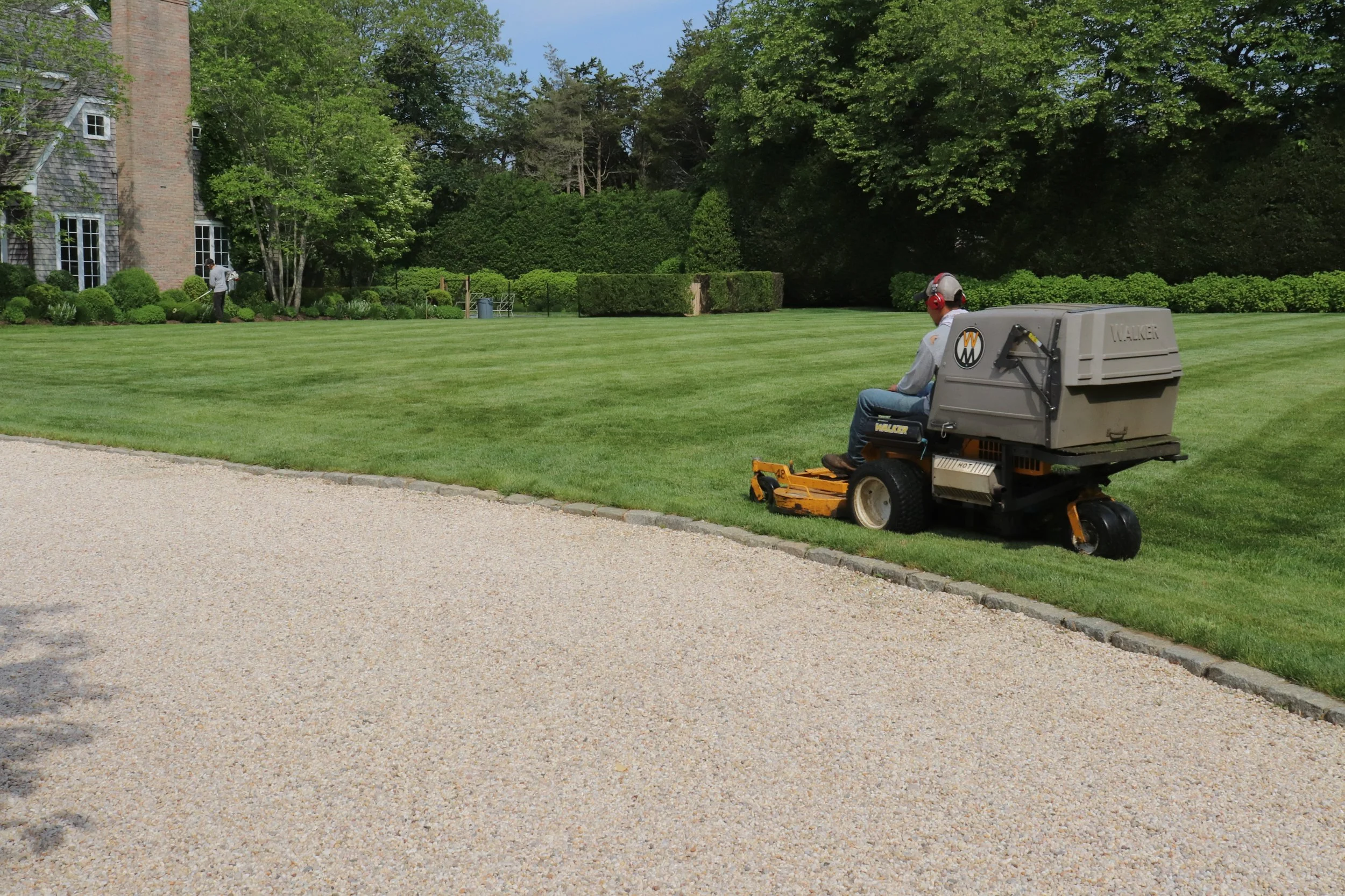 An image of someone riding a lawn mower with a meticulously manicured lawn.