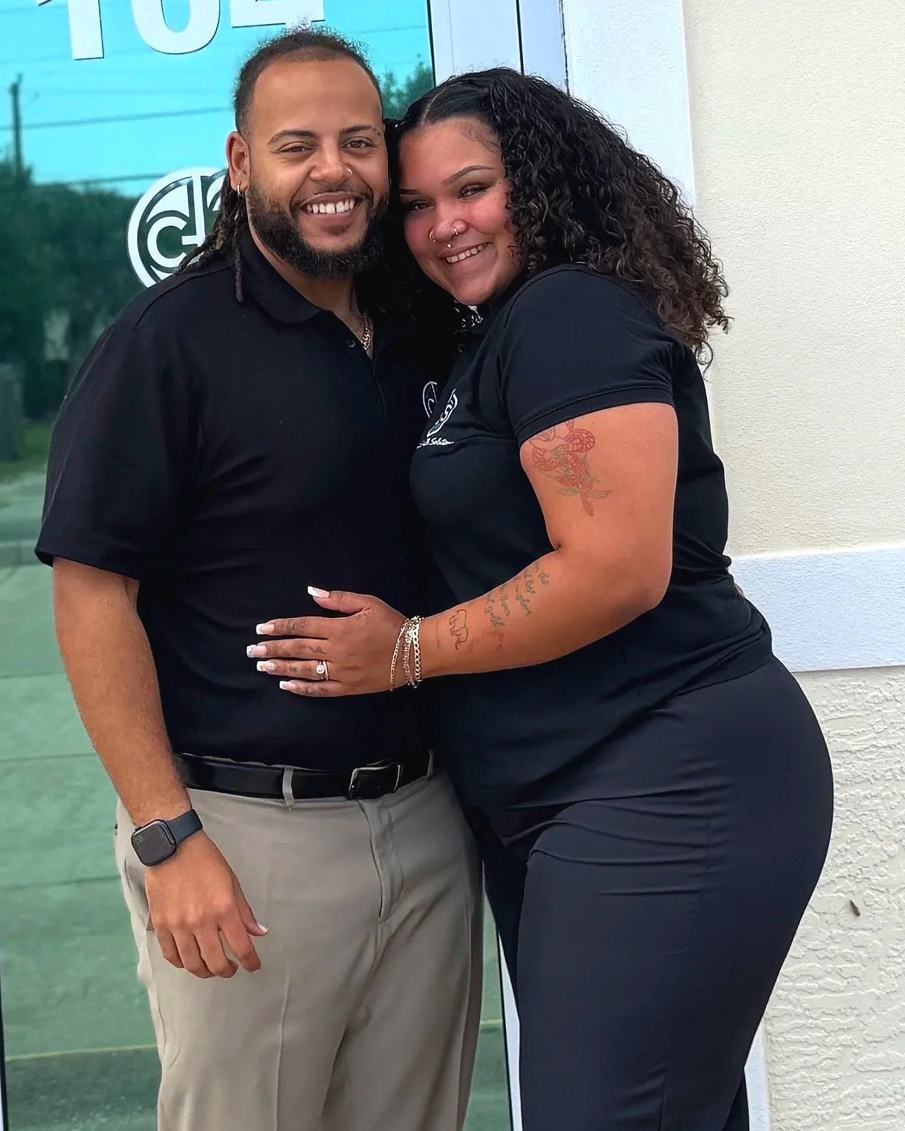 Male and Female with big smile, and hugging in front of office in black shirts