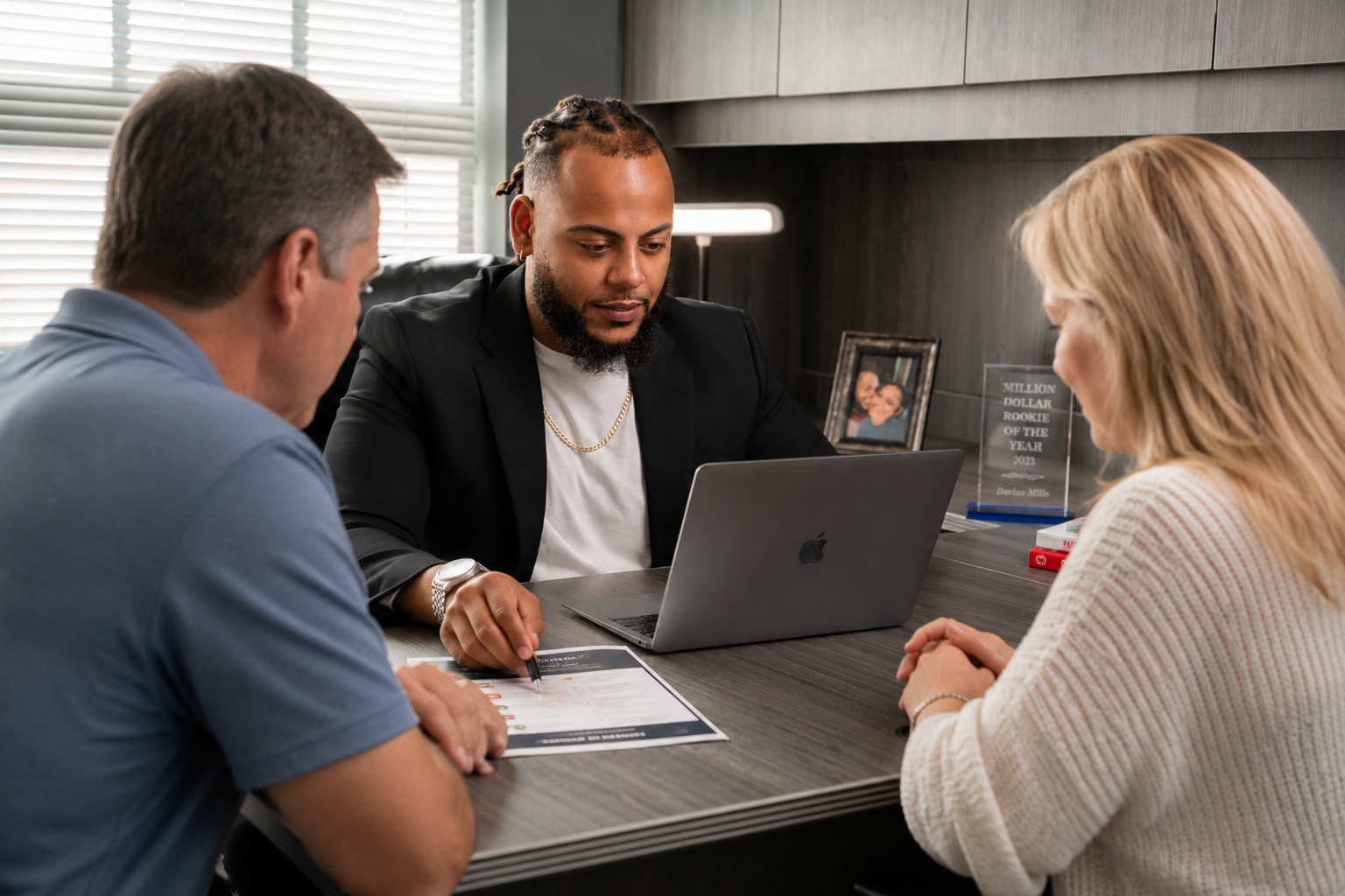 Male with dreads working on computer to help a middle-aged couple with insurance policy