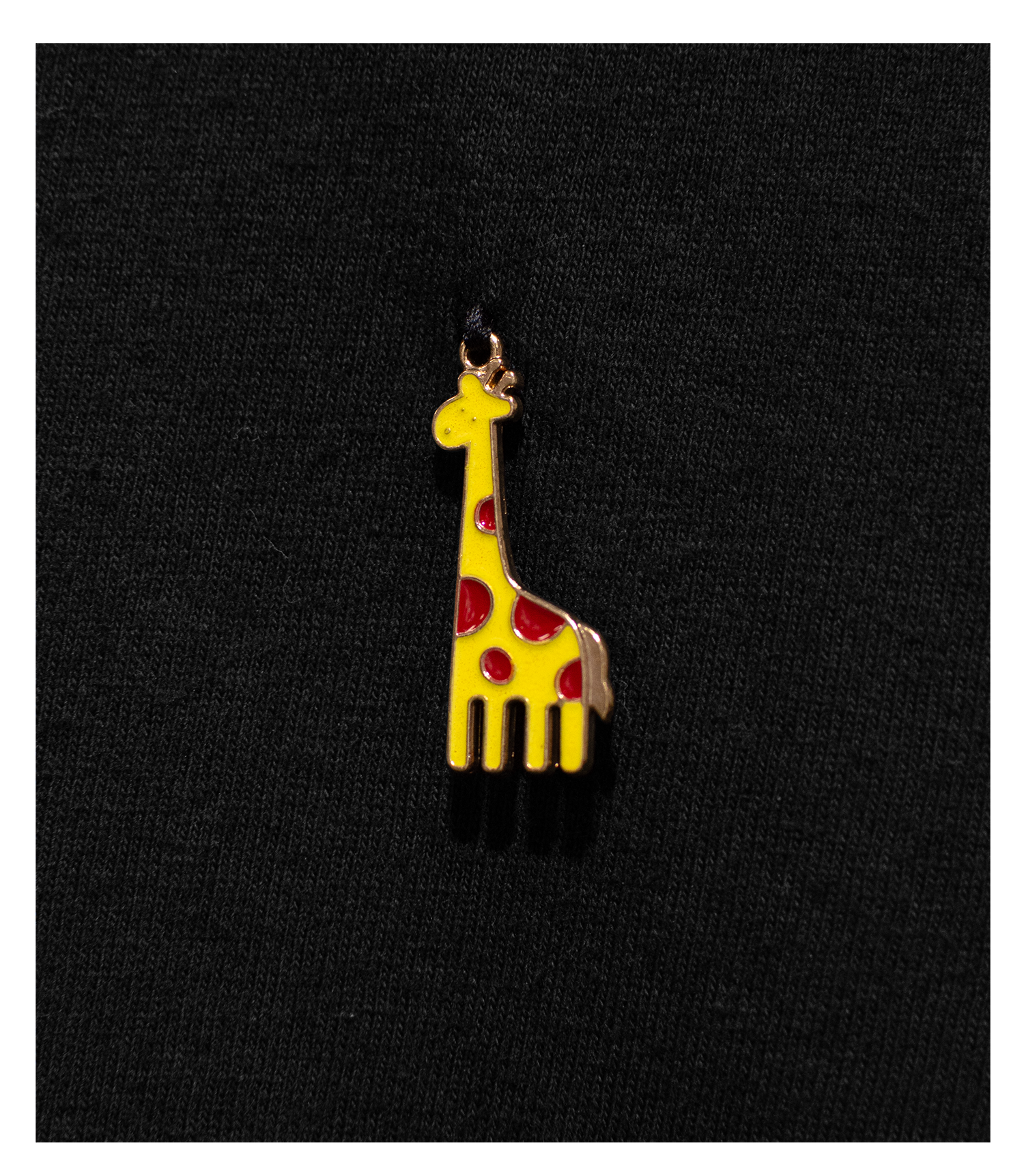 Detail of Black T-Shirt with a yellow and red enamel Giraffe charm sewn to the left chest