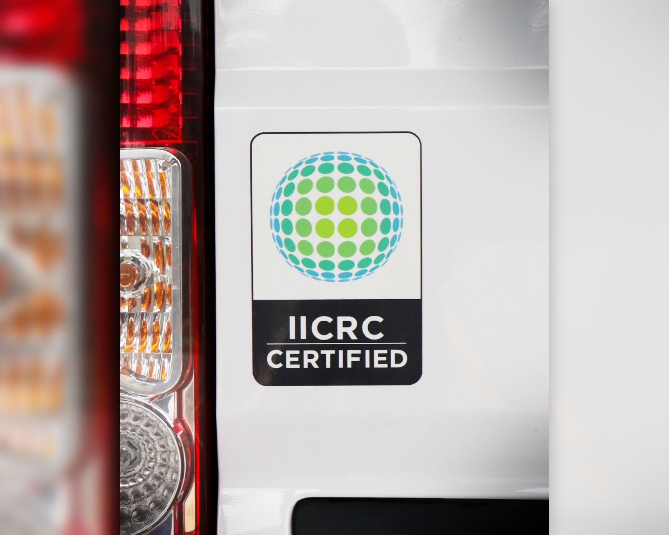 Close-up of a white vehicle with an IICRC certification sticker featuring a colorful globe design.