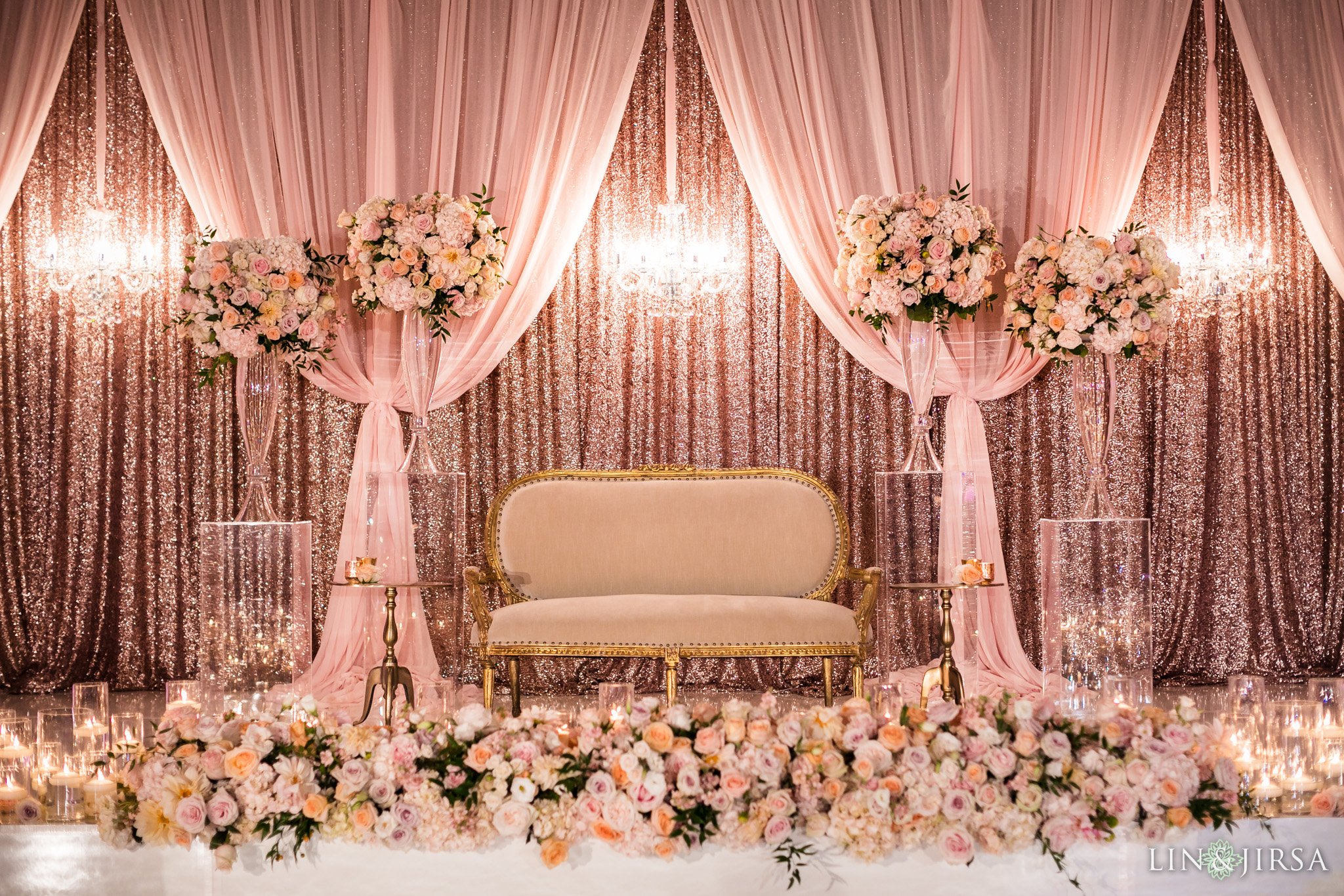 Outdoor wedding ceremony setup with chairs, flower arrangements, a floral arch, and umbrellas in a garden.