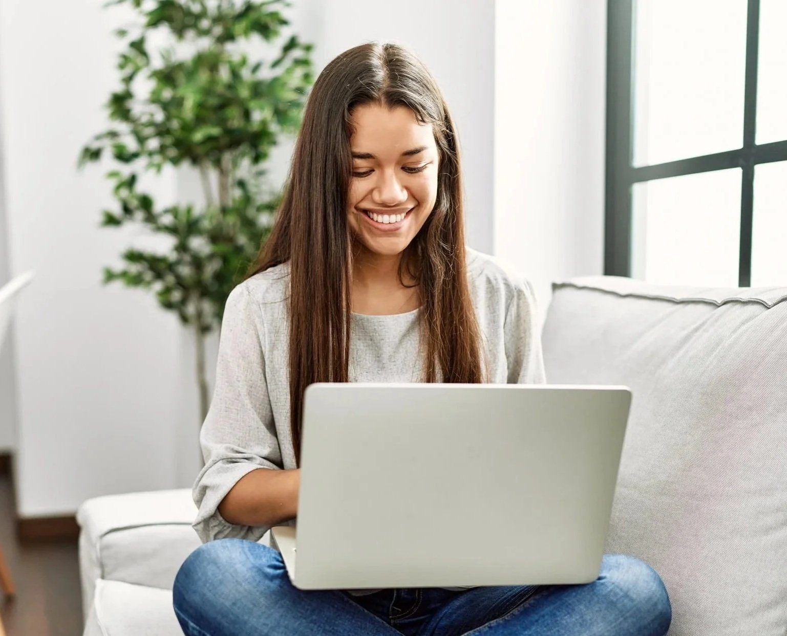 Young latin woman using laptop sitting on sofa at home