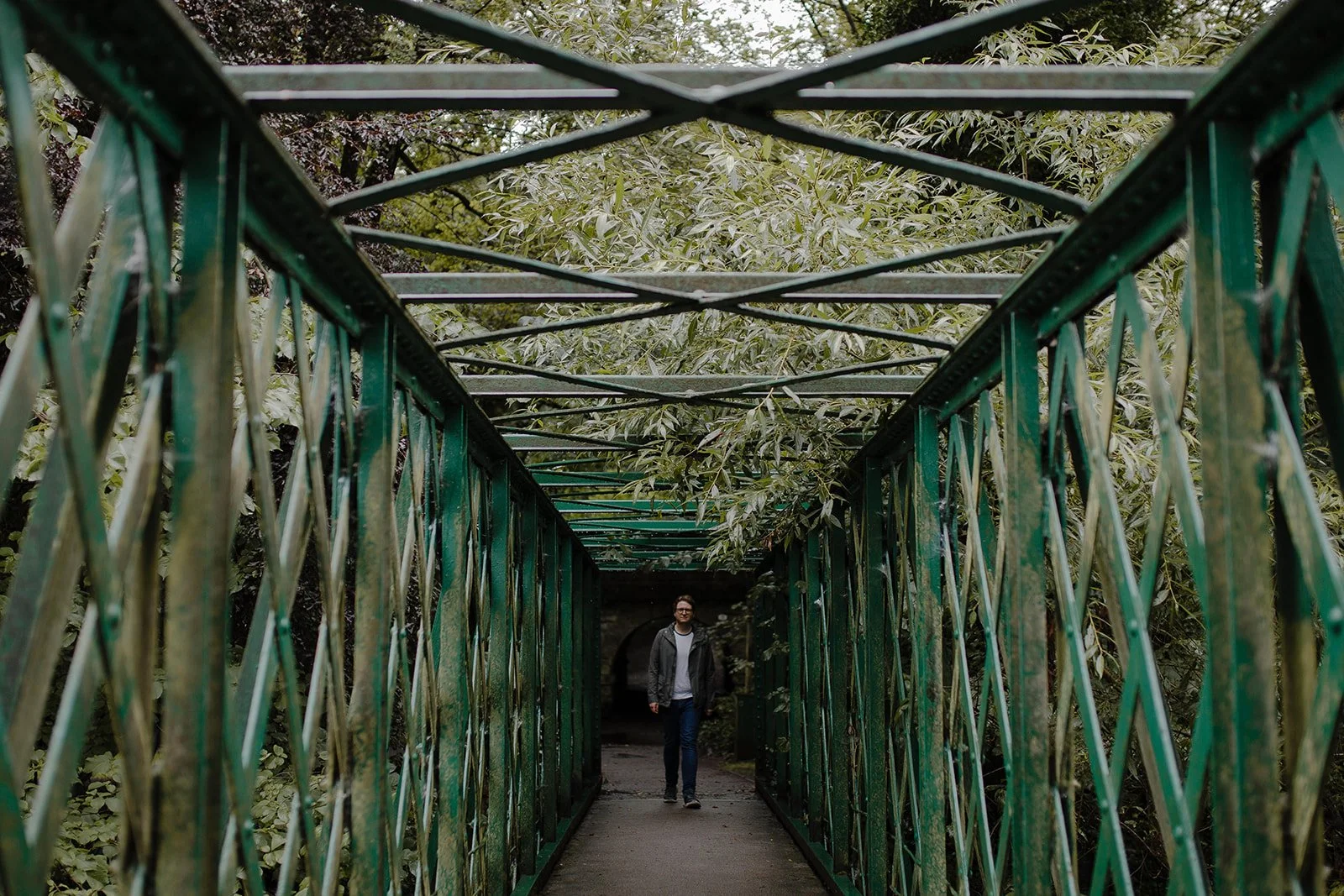 Music teacher walking across a bridge with an umbrella during a thoughtful reflective walk