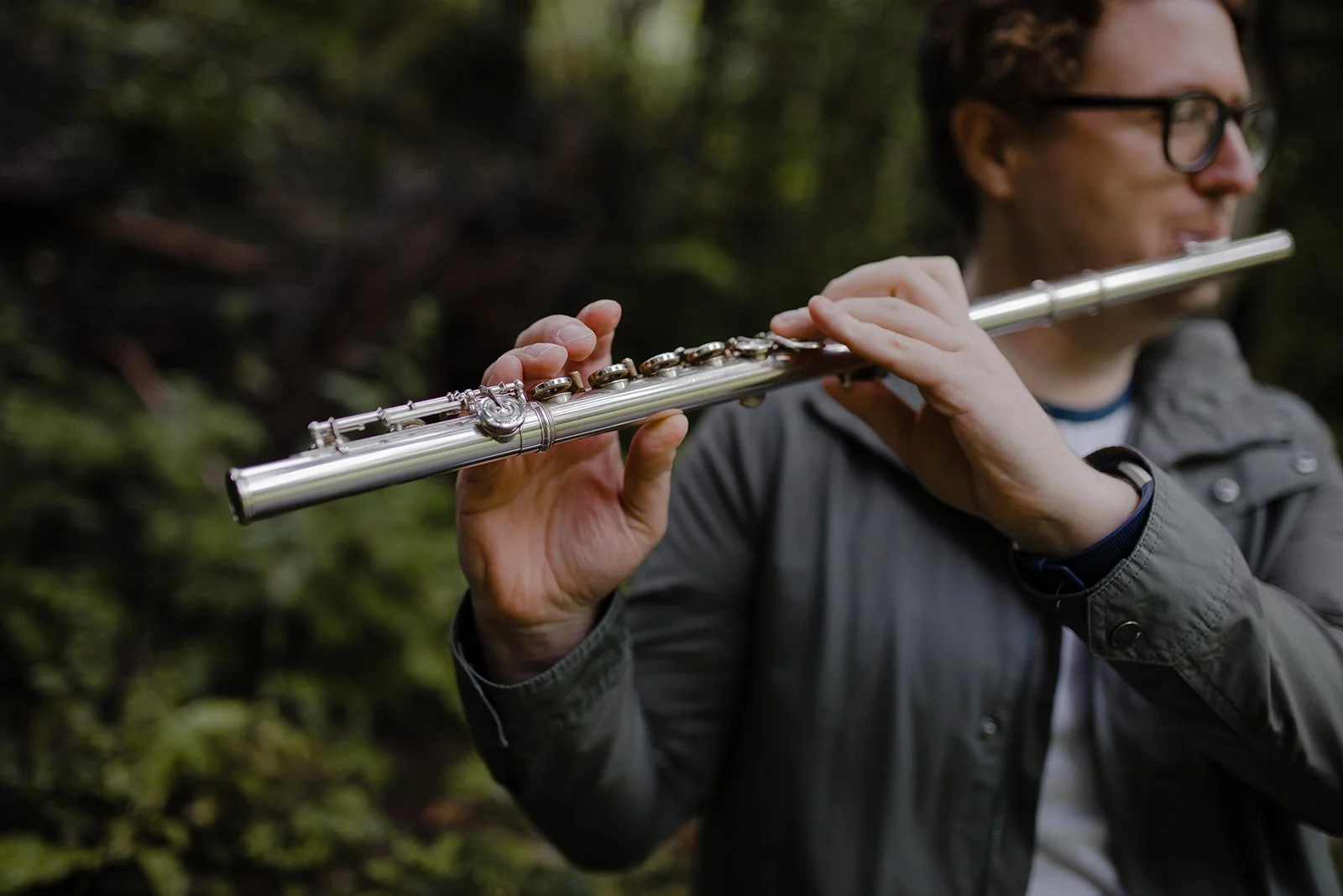Private music teacher playing the flute in a forest
