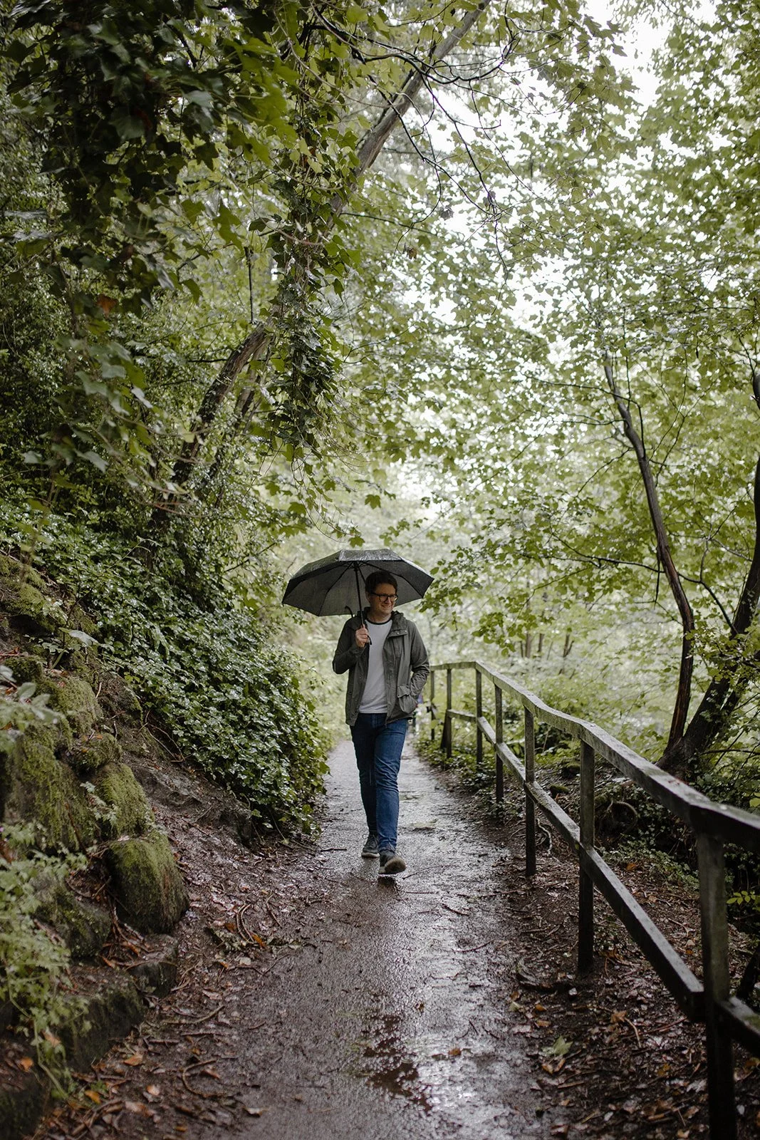 David Barton walking beside a river in the rain with an umbrella, illustrating the importance of rest and reflection in sustainable music teaching.