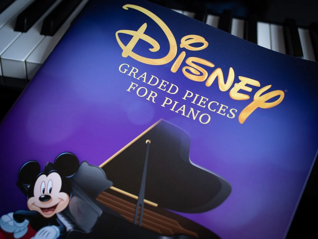 Front cover of Disney Graded Pieces for Piano, a collection of graded piano sheet music featuring music from Disney films.