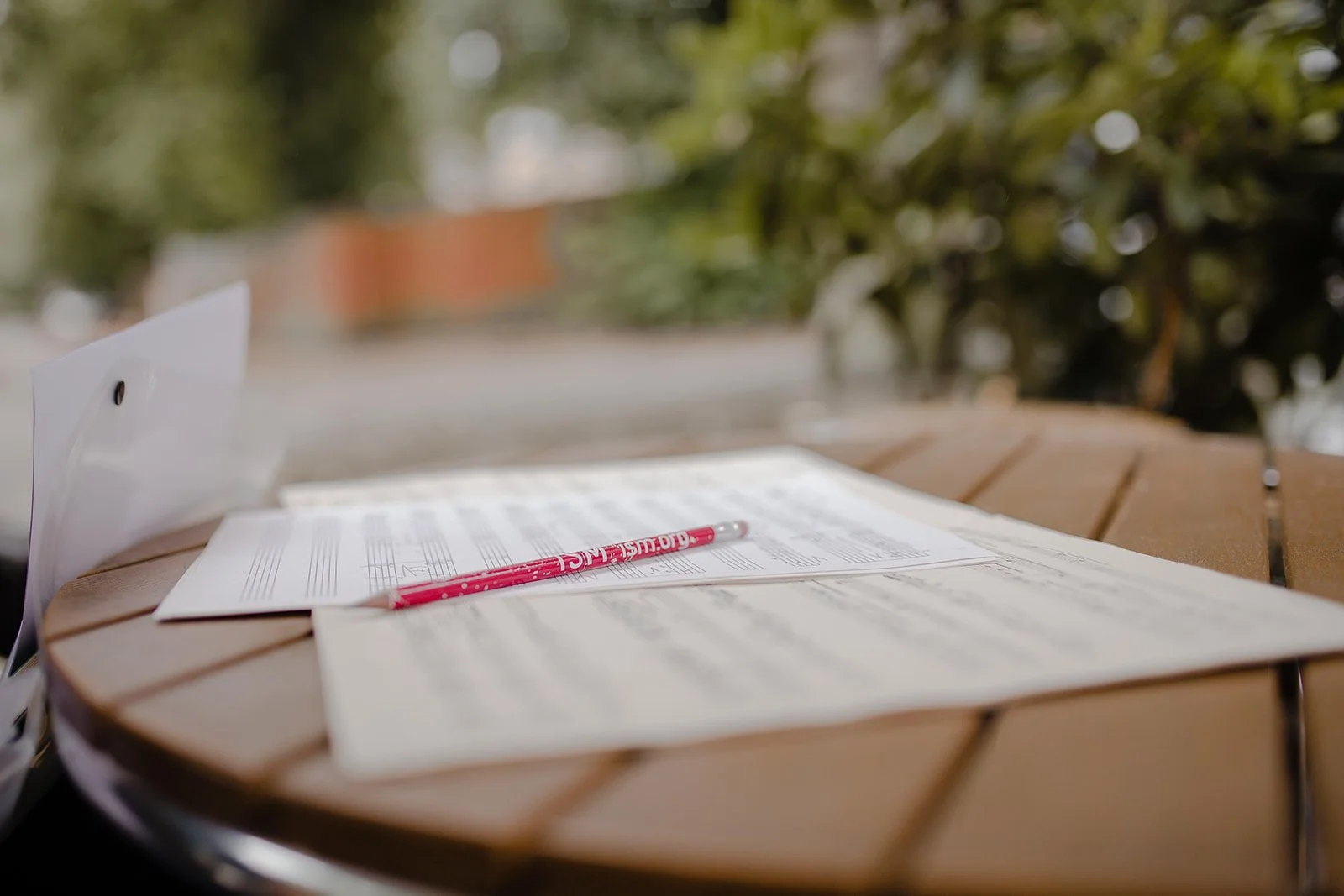 Manuscript paper and pencil on an outdoor table, representing creativity, reflection, and balance in music teaching.