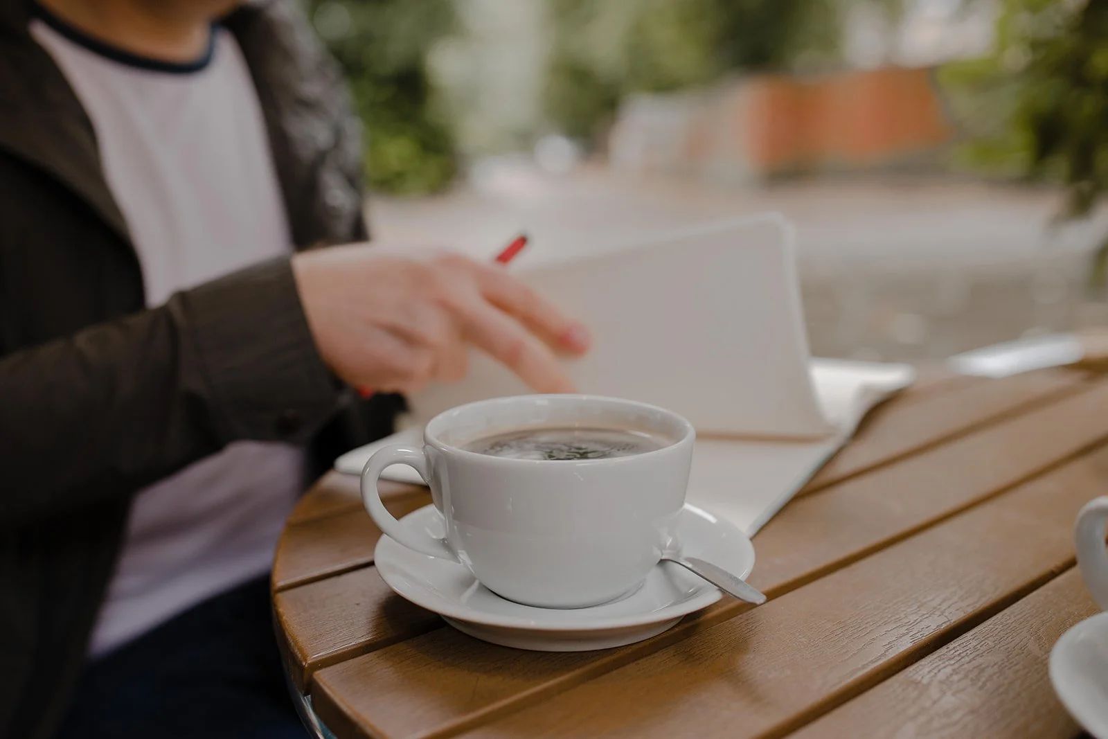 Music teacher sitting in a café with coffee and a notebook reflecting on teaching and studio life