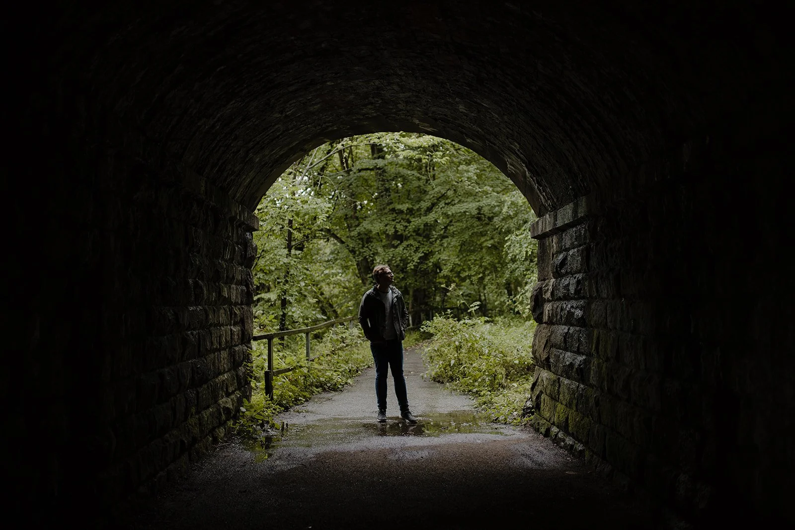 Silhouette of a music teacher standing beneath a bridge looking upwards in reflection