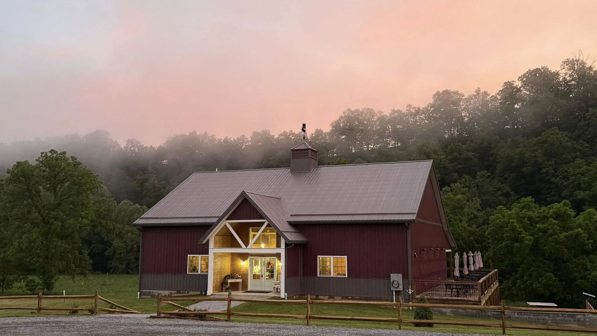 Old World Libations winery and tasting room just after a summer rain, with warm lights glowing against the misty wooded hills of Monroe County, West Virginia. A peaceful Appalachian setting for wine, mead, cider, and time well spent.