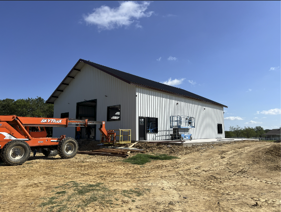 New metal industrial warehouse under construction with an orange Skytrak telehandler parked outside