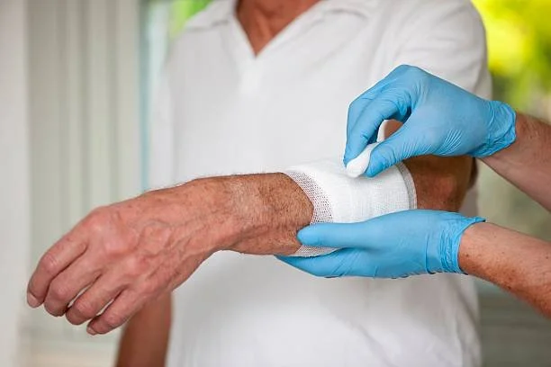 Nurse bandaging elderly resident's arm following injury