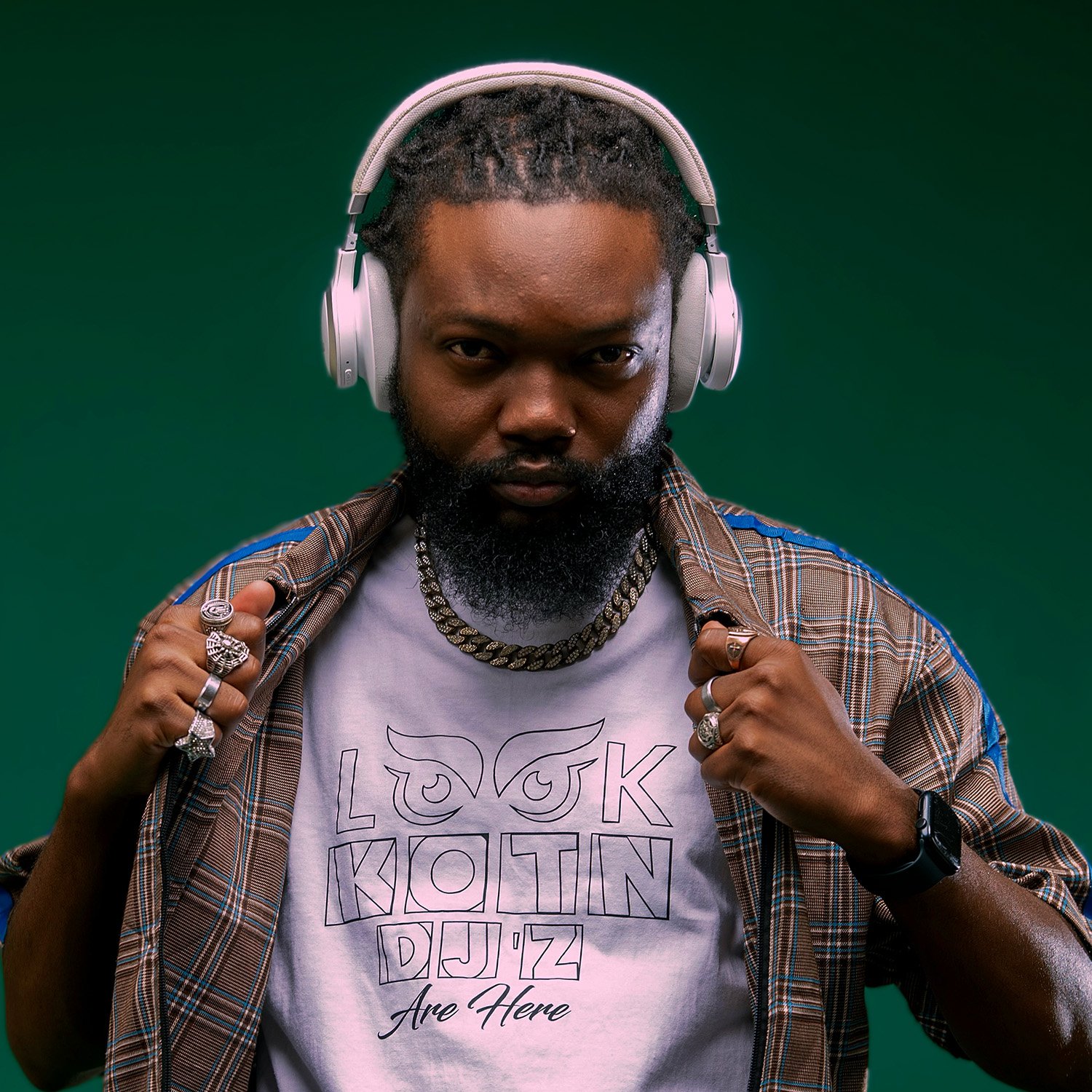 Man wearing headphones, a plaid shirt, and a graphic tee with text "Look Kotin DJ'z Are Here."