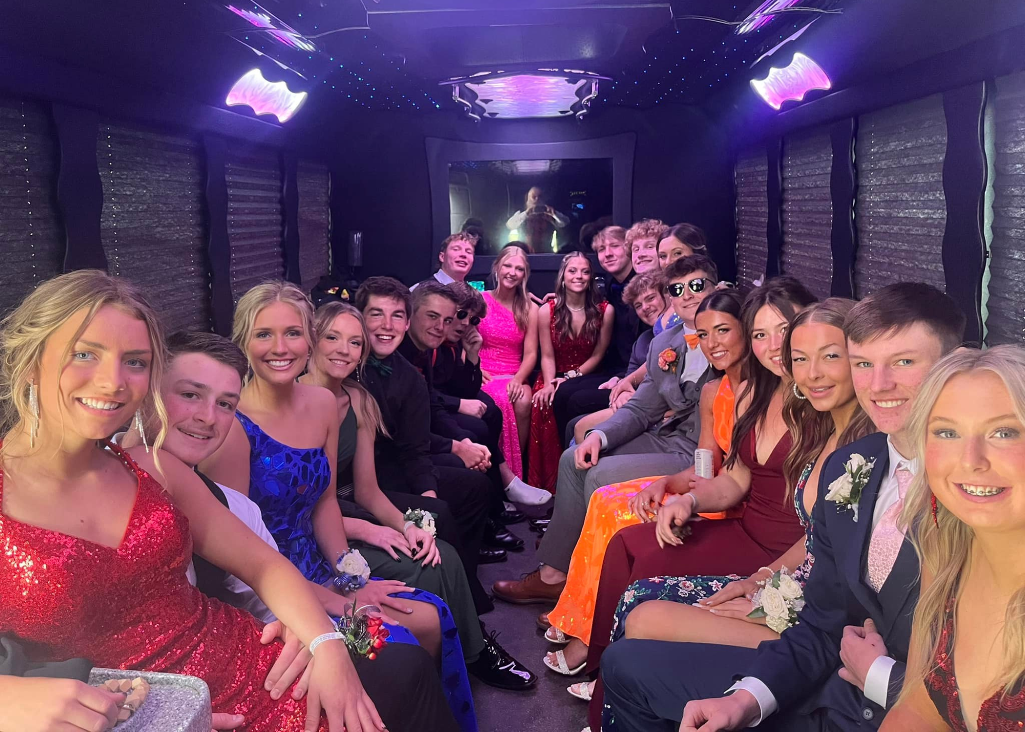 Prom group dressed up and smiling beside Okoboji party bus rental for prom night