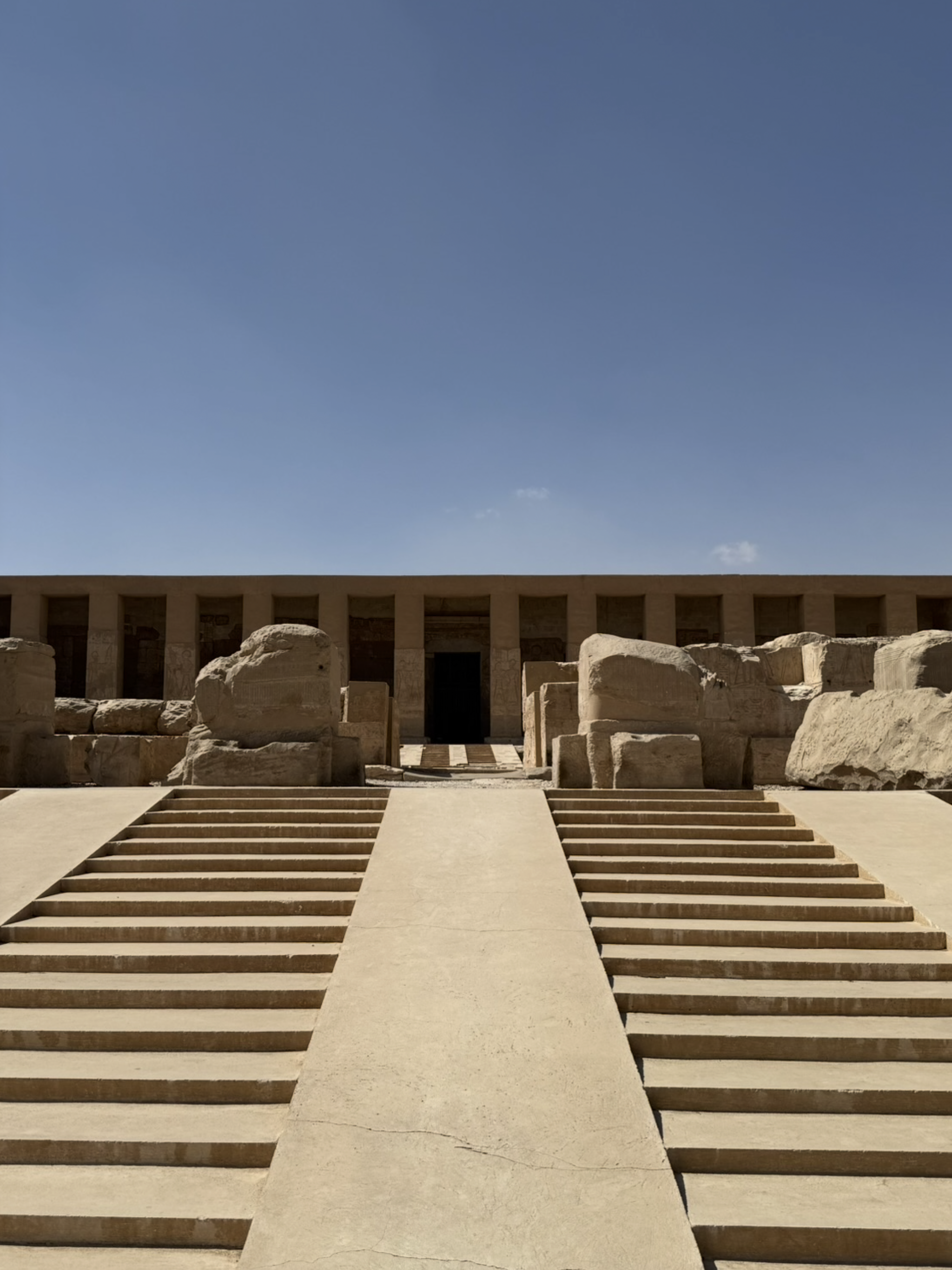Stone steps leading up to a doorway with large stone blocks on either side, under a clear blue sky.
