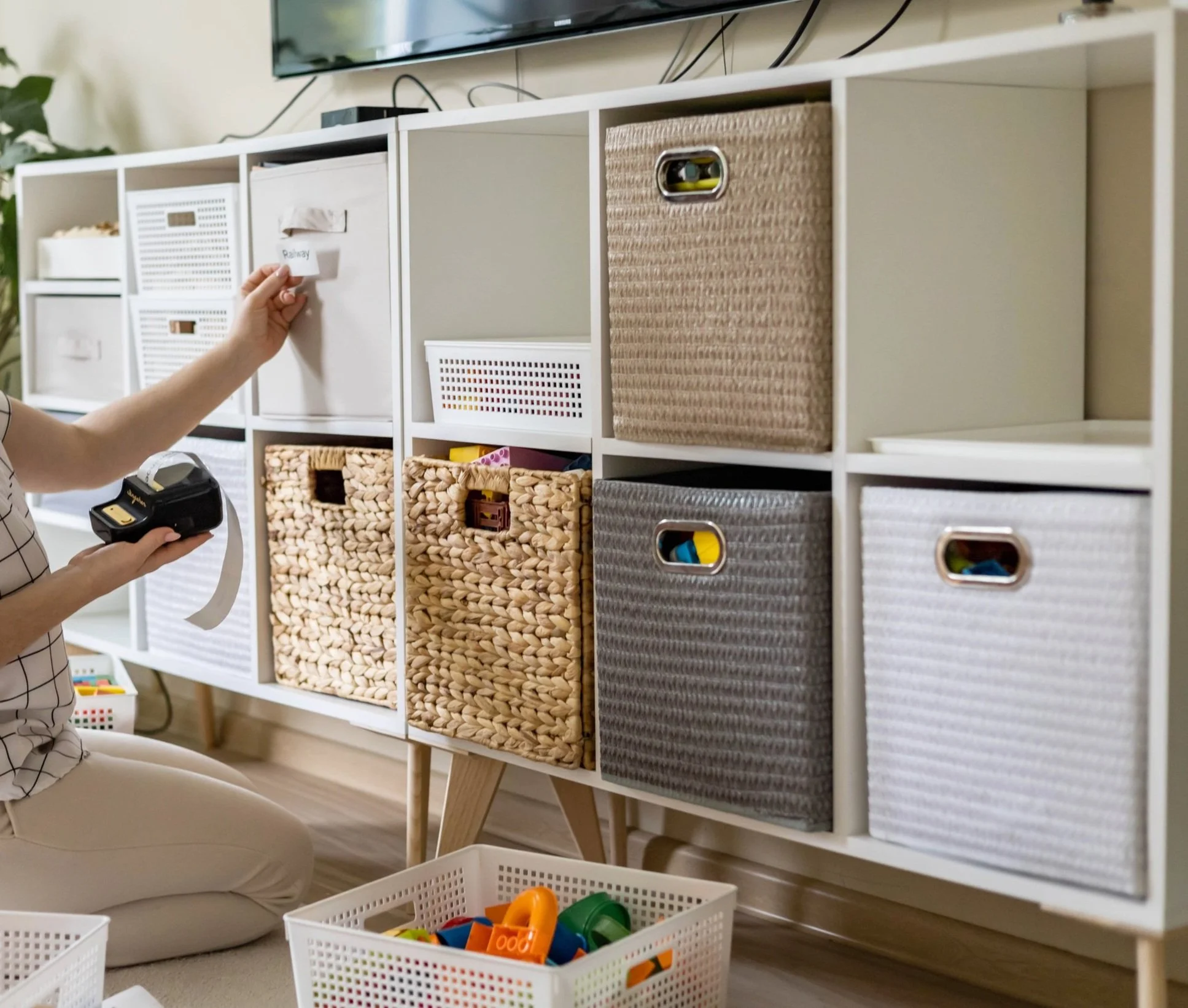 smiling-woman-applying-paper-print-sticker-title-inscription-kids-toy-storage-organizing-home.jpg