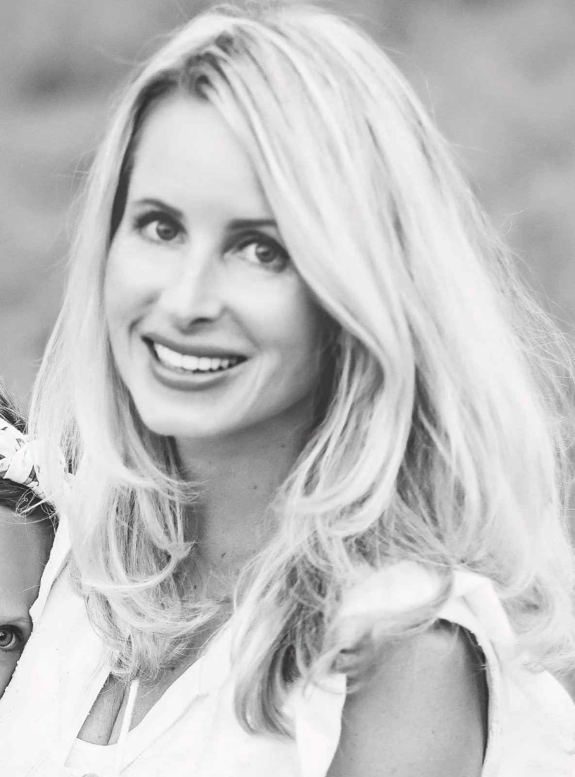 Black and white photo of a woman with long, wavy hair smiling at the camera.
