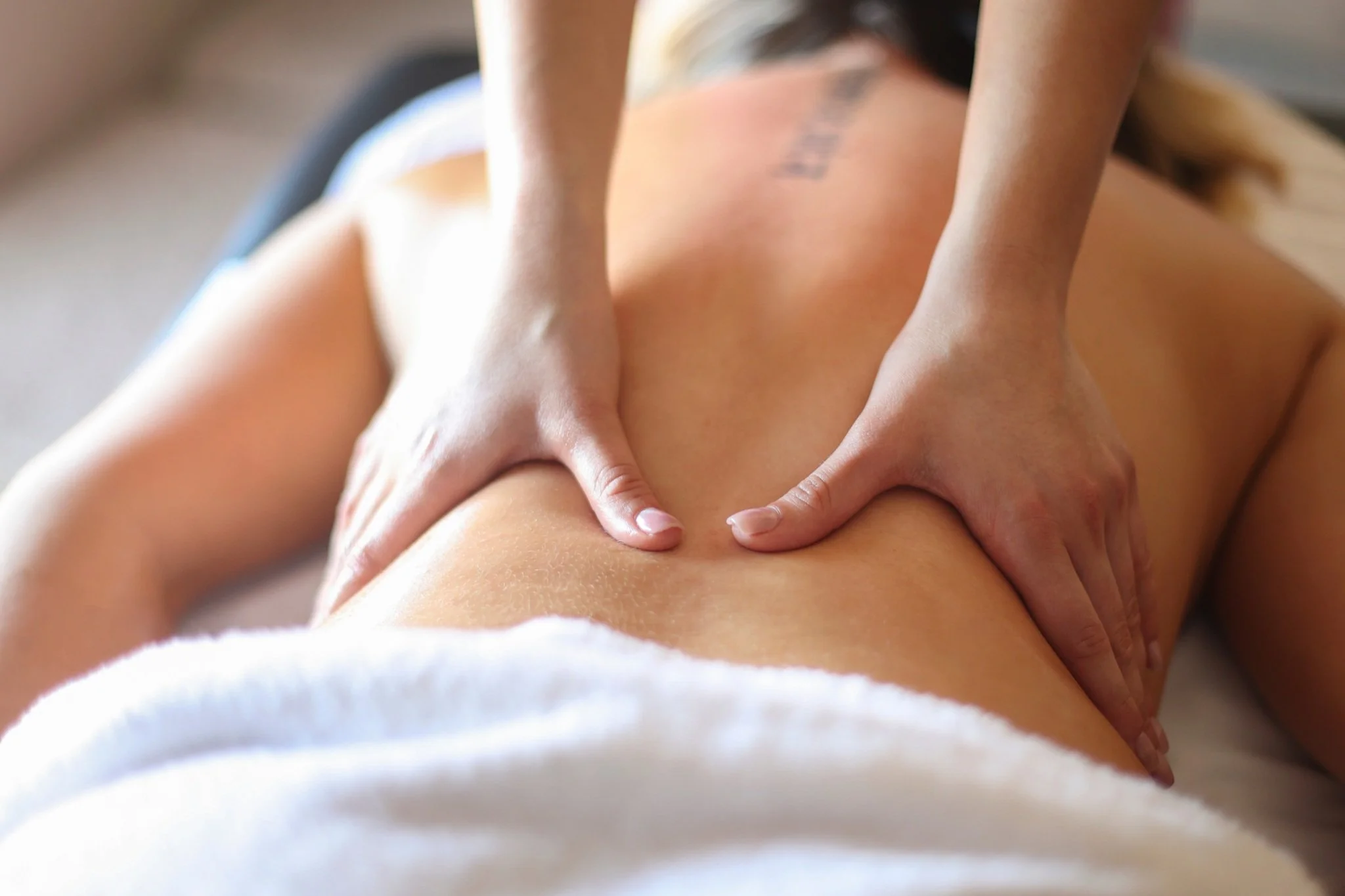 Person receiving a massage on their back by a massage therapist.