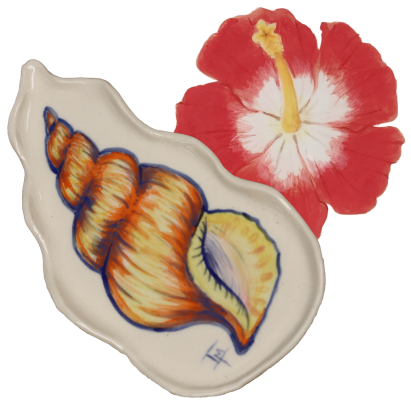 A decorative ceramic dish shaped like a conch shell with a painted orange and yellow pattern and a blue eye, placed next to a bright red hibiscus flower.