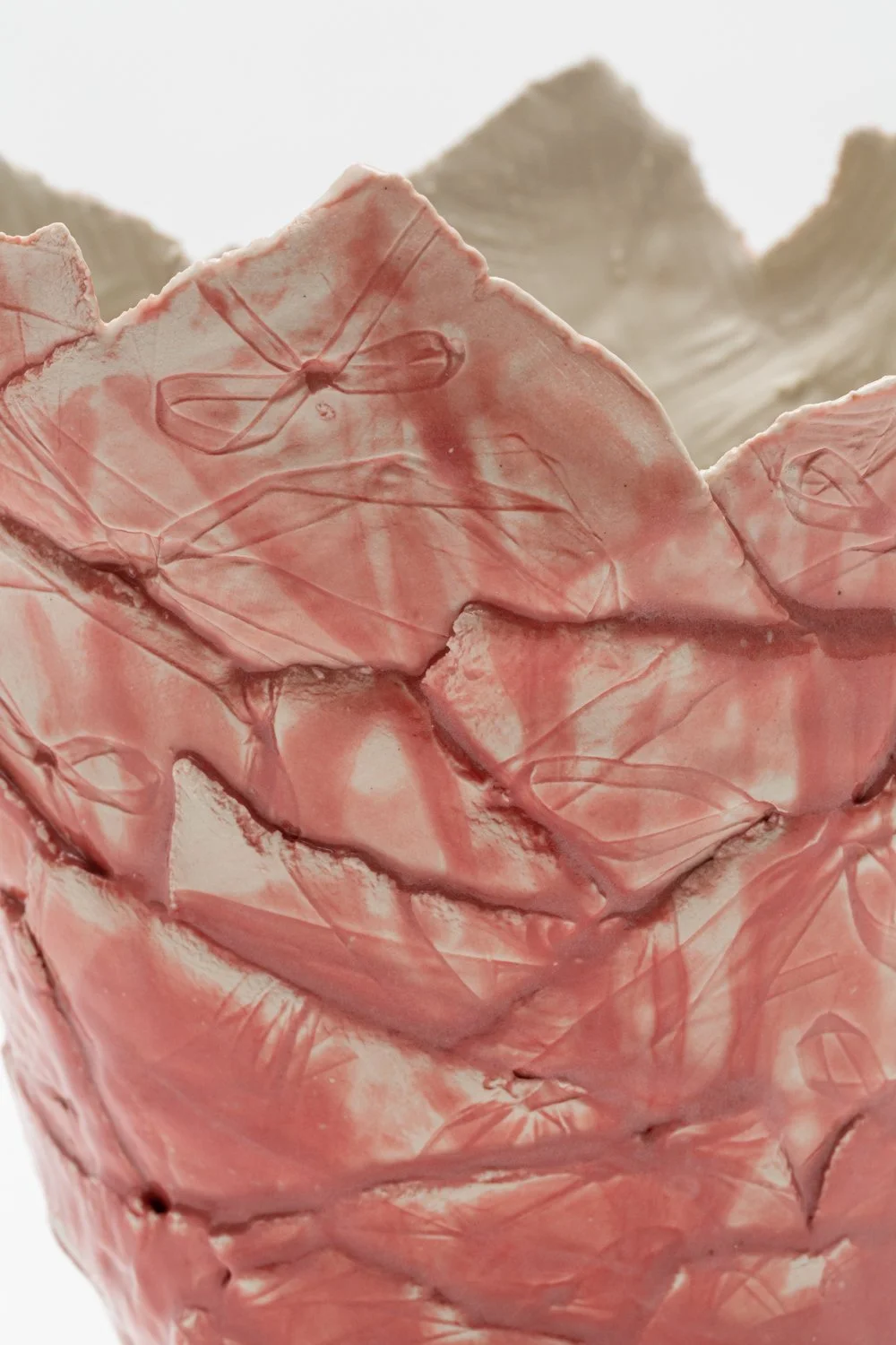Close-up of pink and white vase with leaf-like patterns.