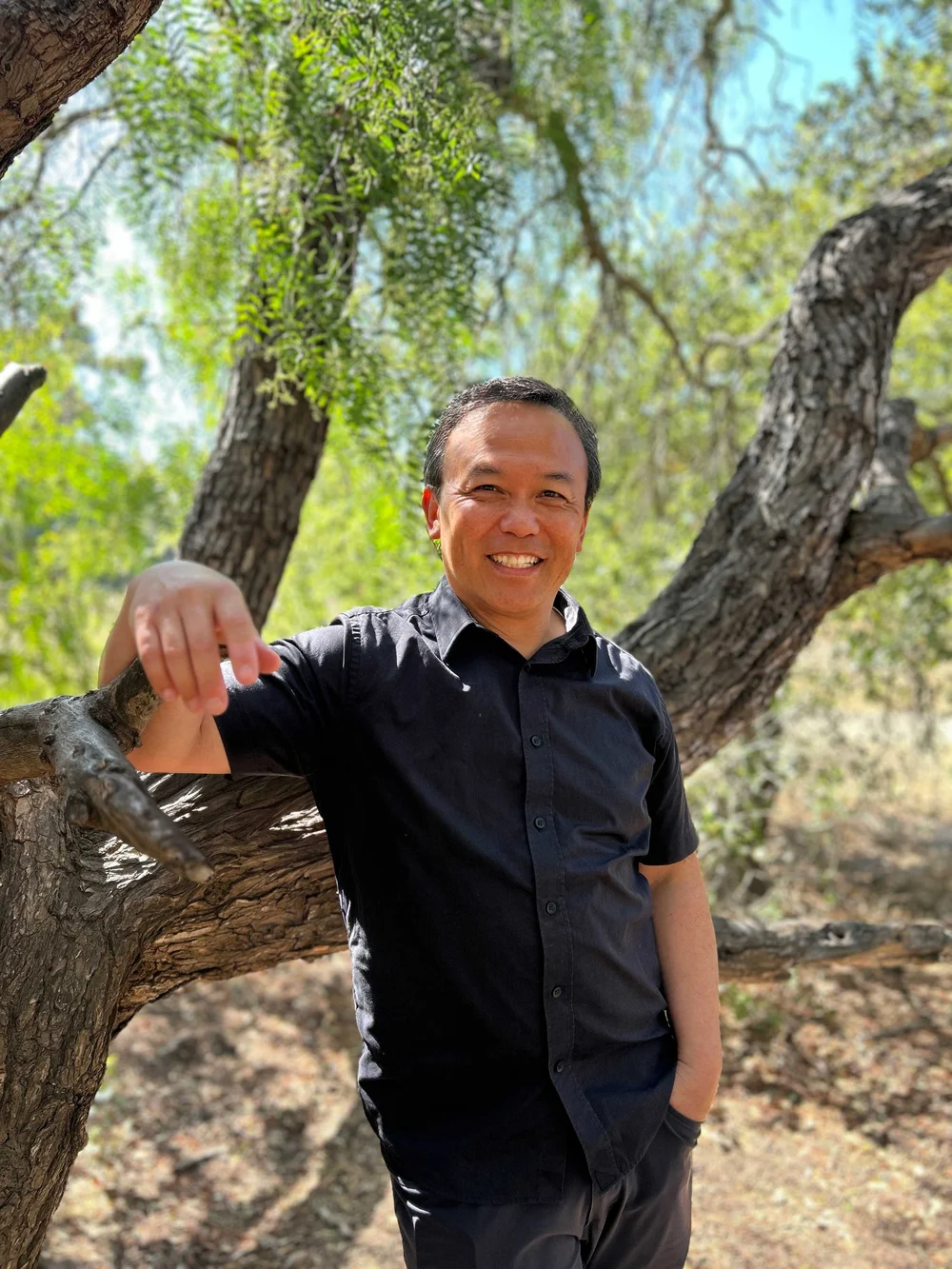 Tim Yee outdoors beside a tree
