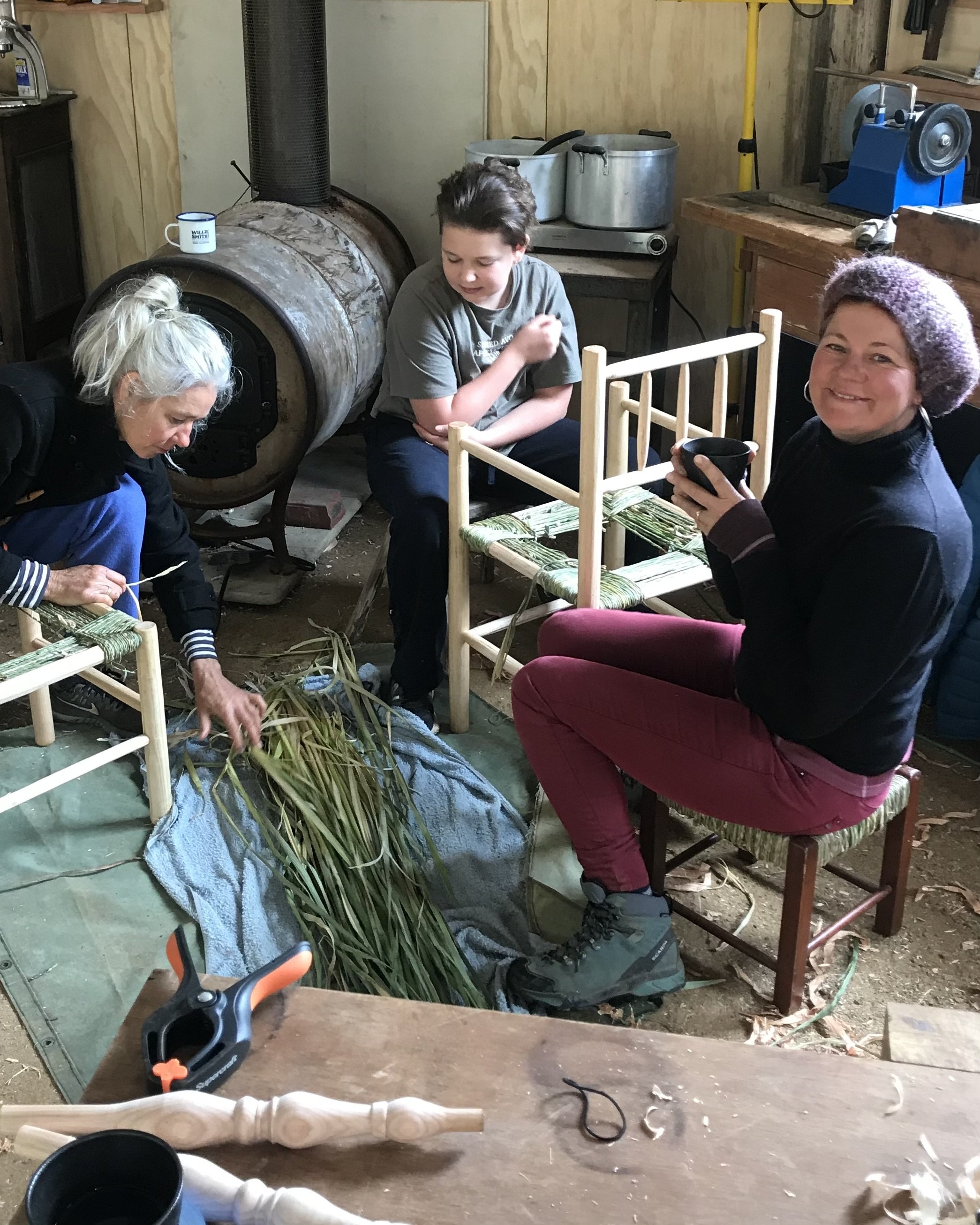 Happy workshop participant in the Wisdom Through Wood workshop, holding his hand-crafted green wood stool.