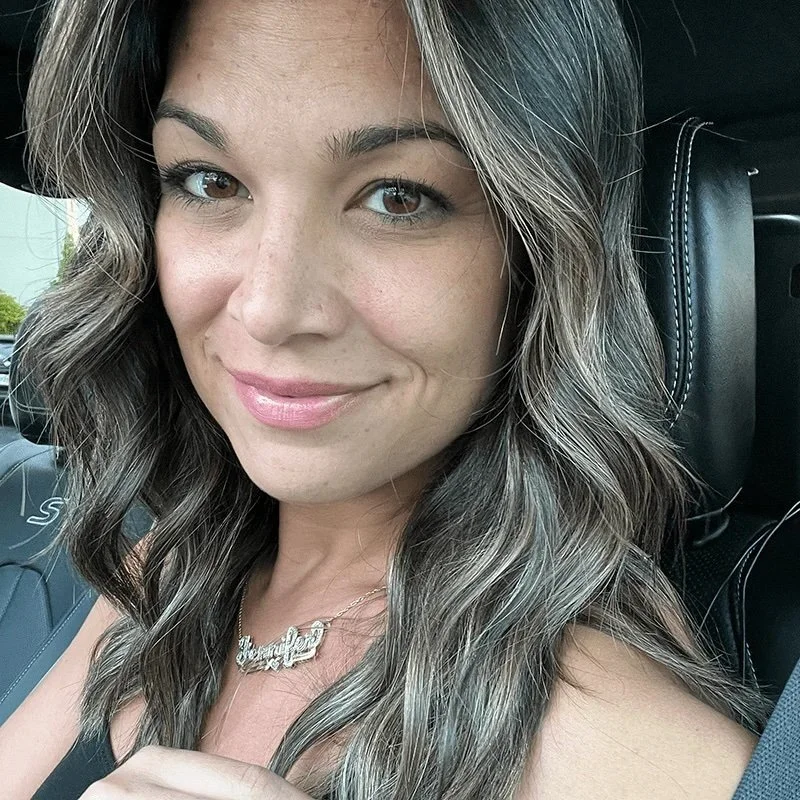 Close-up of a woman with wavy hair, smiling in a car.