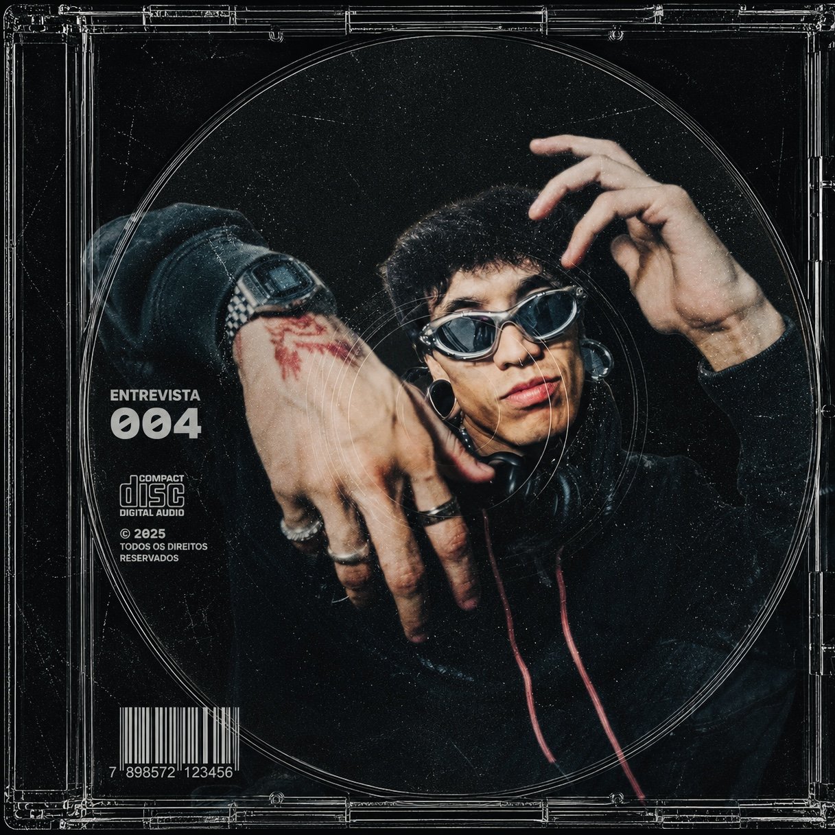 Capa de álbum com uma pessoa usando óculos escuros e roupas de estilo alternativo, ao fundo é possível ver detalhes de um CD, com o texto 'Entrevista 004'.