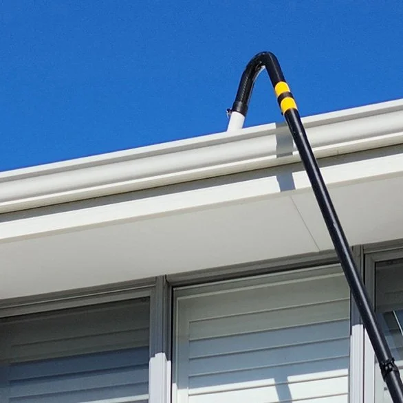 A gutter cleaning vacuum pole attached to a long extendable pole leaning against a house gutter under a clear blue sky in Melville, Perth WA