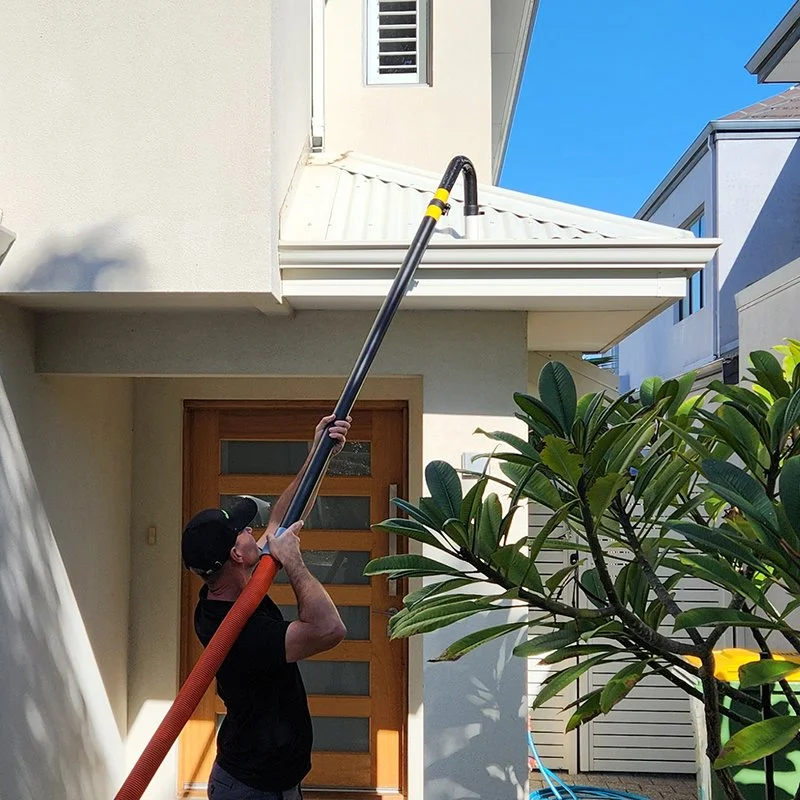 Cleaning gutters with vauum on extended pole to reach high gutters