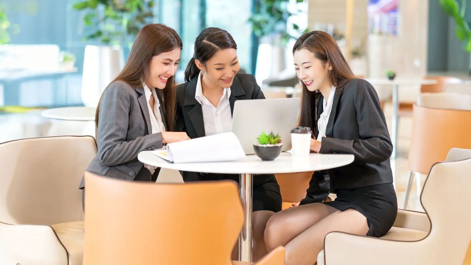 A group of Asian female HR professional reviews a laptop