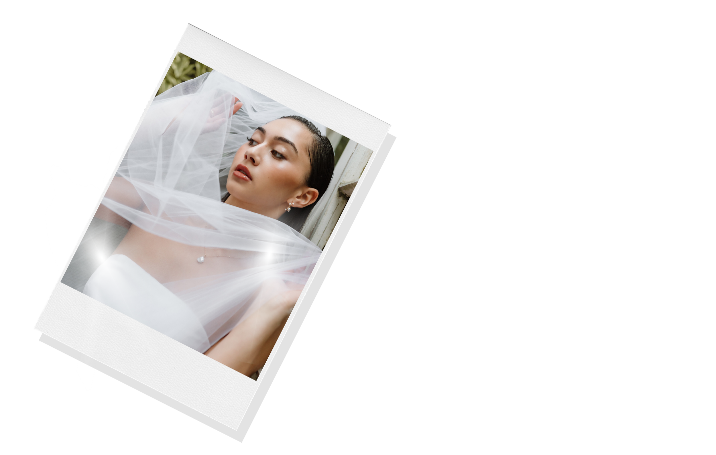 Close-up shot of bride with wedding veil and soft glam makeup peeking through polaroid photo frame