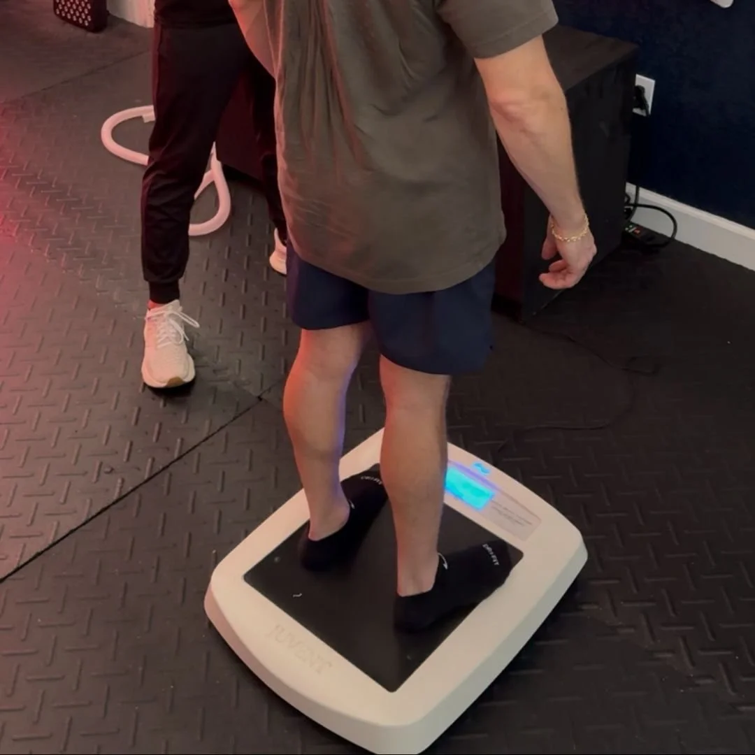 Person standing on digital weight scale with digital display showing weight, on black rubber gym floor.