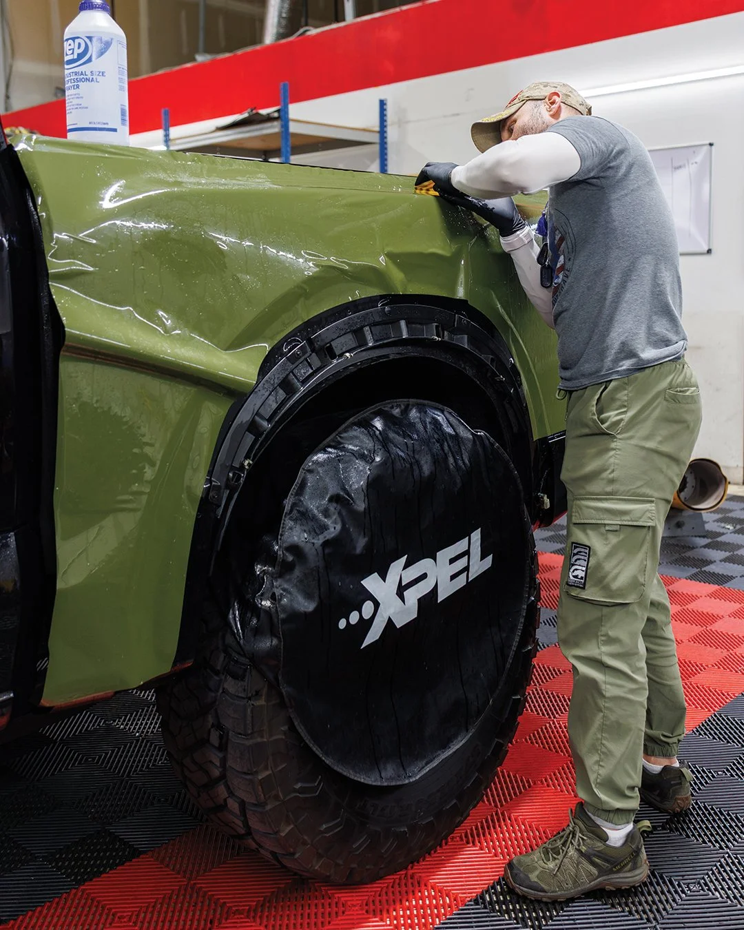 A person working on the front of a vehicle applying paint protection film (PPF).