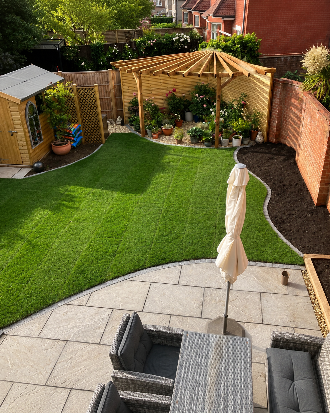 Completed garden landscaping with a curved patio, lawn, timber screening and pergola.
