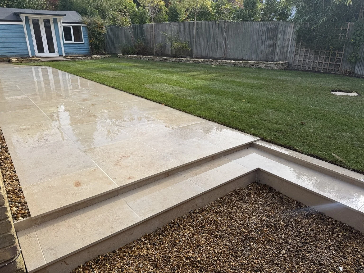 Completed porcelain patio with steps and lawn edging.