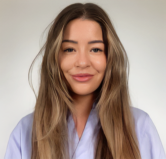 A young woman with long, wavy hair and a subtle smile, wearing a light purple top against a plain, light background.