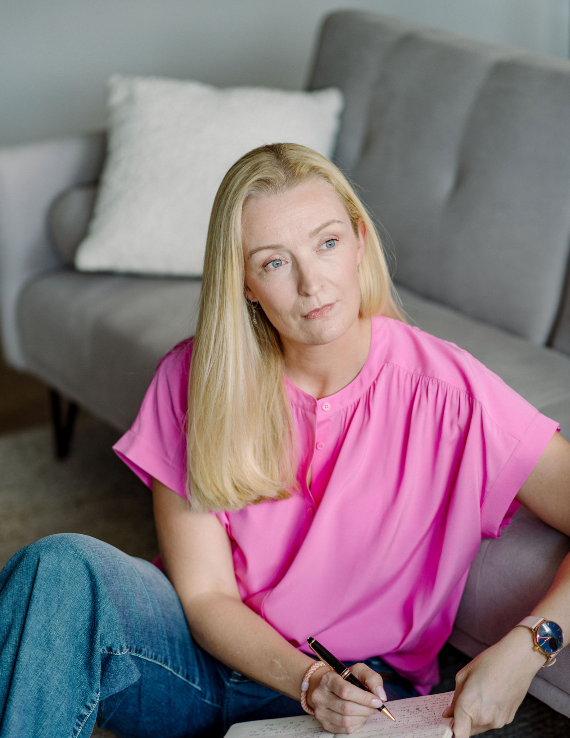 Frau sitzt nachdenklich auf dem Boden und schaut in die Ferne, passend zu belastende Erfahrungen und Psychotherapie