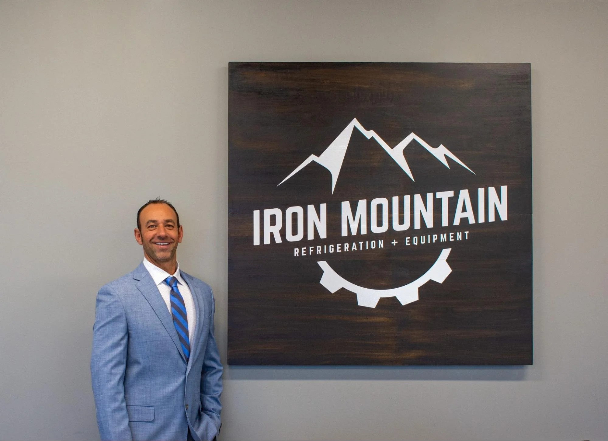evor Crivello, Founder and CEO of Iron Mountain Refrigeration, standing beside the Iron Mountain sign