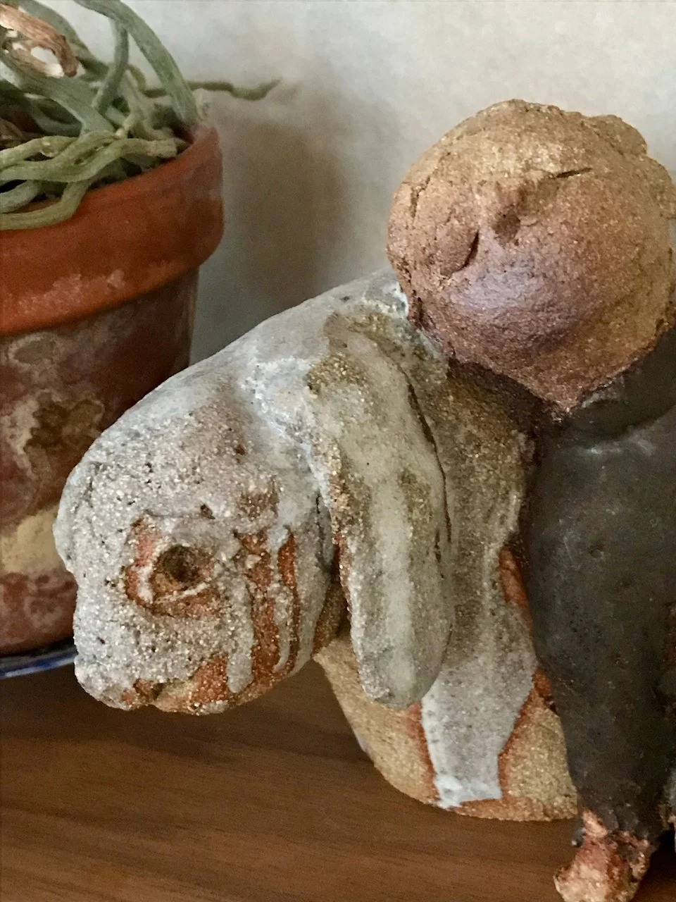 jente og kanin i steingodsleire, jentefigur i brun glasur, kanin i lysgrå glasur, står på hylle, detalj av ansikt