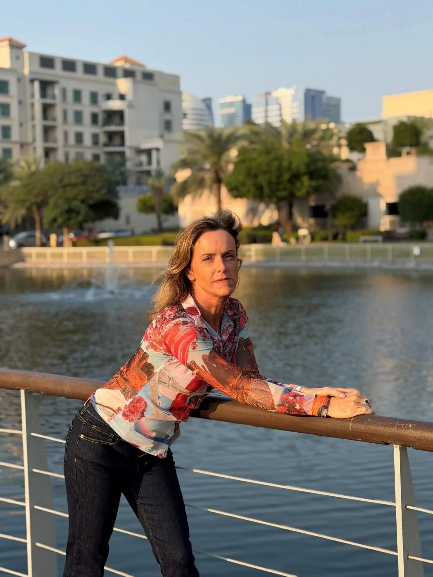 Michela Modolo standing in front of water, leaning on a railing with arms outstretched