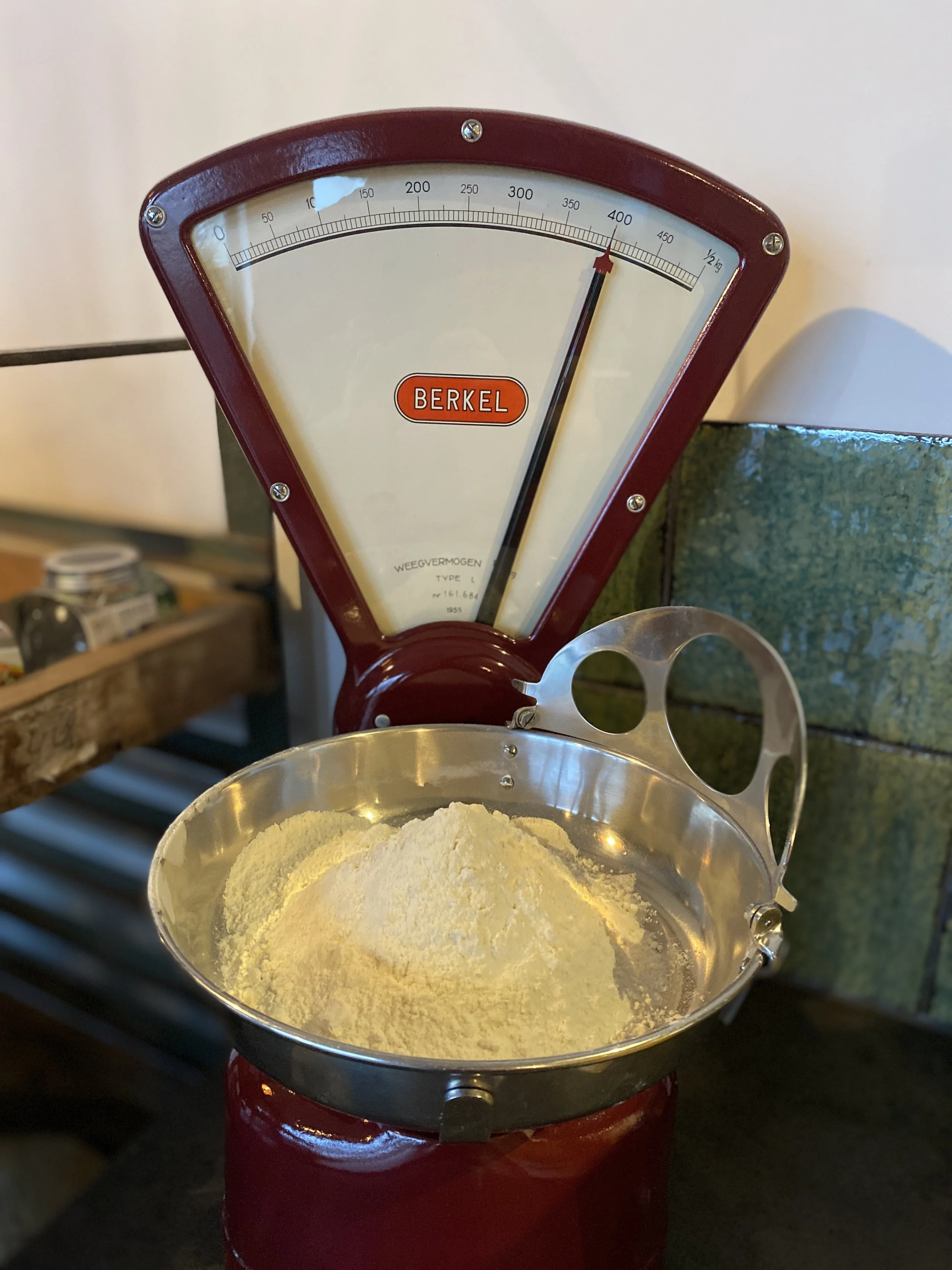 Red vintage kitchen scale with flour in a metal bowl on top.