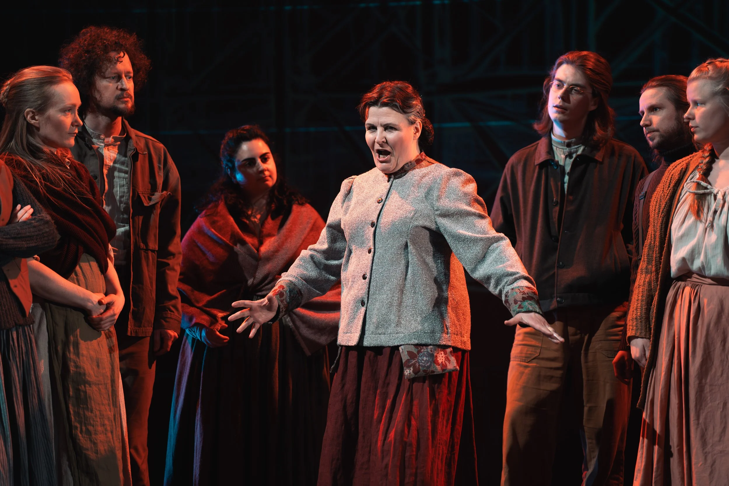 Näyttelijä tekee draamatan näytöksessä, ympärillä muita näyttelijöitä, kohtaus teatterissa.