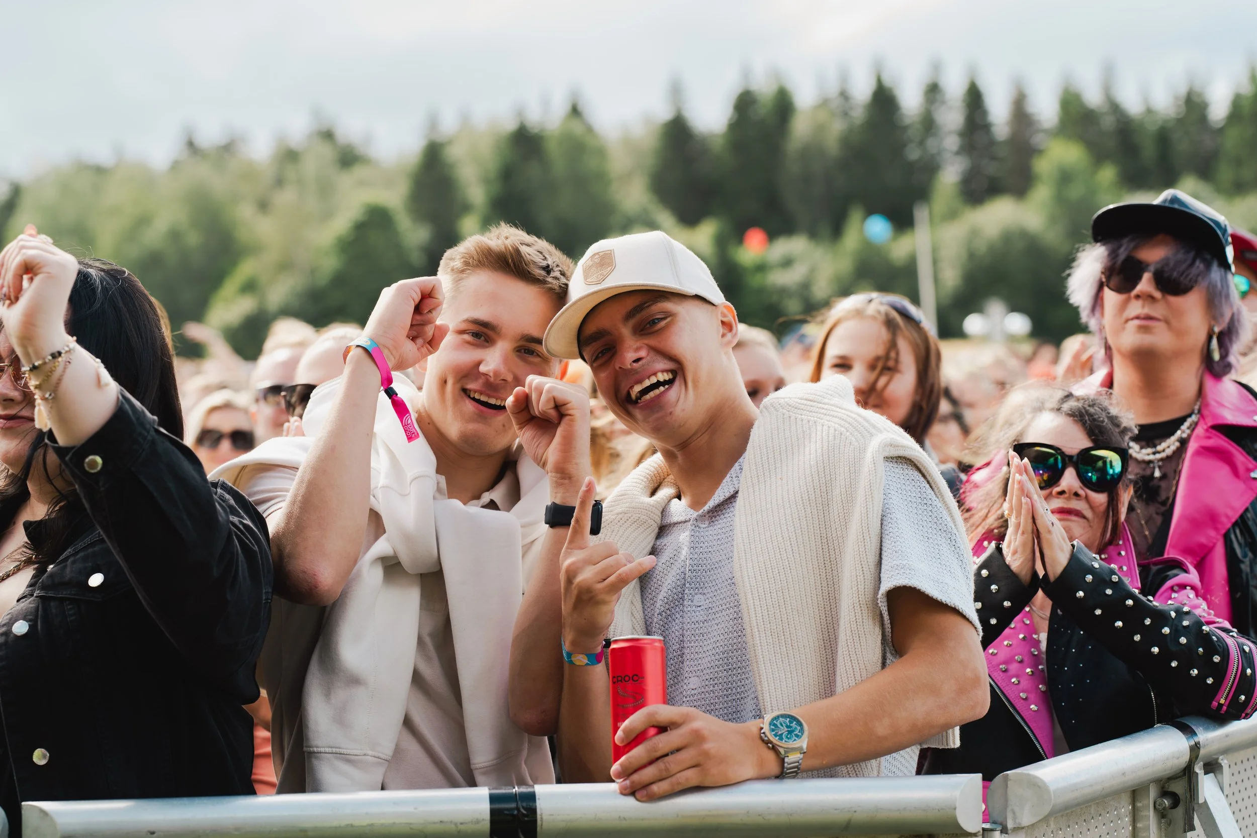 Iloisia nuoria ja aikuisia juhlijoita festivaalialueella ulkona, taustalla puumetsä.